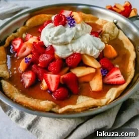 A decadent Dutch Baby Puff Pancake, a German pancake recipe made with milk, eggs, sugar, flour, and vanilla, baked in a cast iron skillet until puffed and golden brown, offering an easy and delicious breakfast.