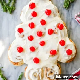 A festive Cinnamon Roll Christmas Tree, made with homemade or store-bought cinnamon roll dough, elegantly shaped into a tree and adorned with creamy frosting and red cherry 'ornaments'.