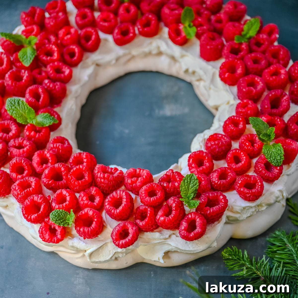 Festive Pavlova Cloud 4 Overhead view of a Christmas Pavlova wreath adorned with red raspberries and green mint, showcasing its festive design.
