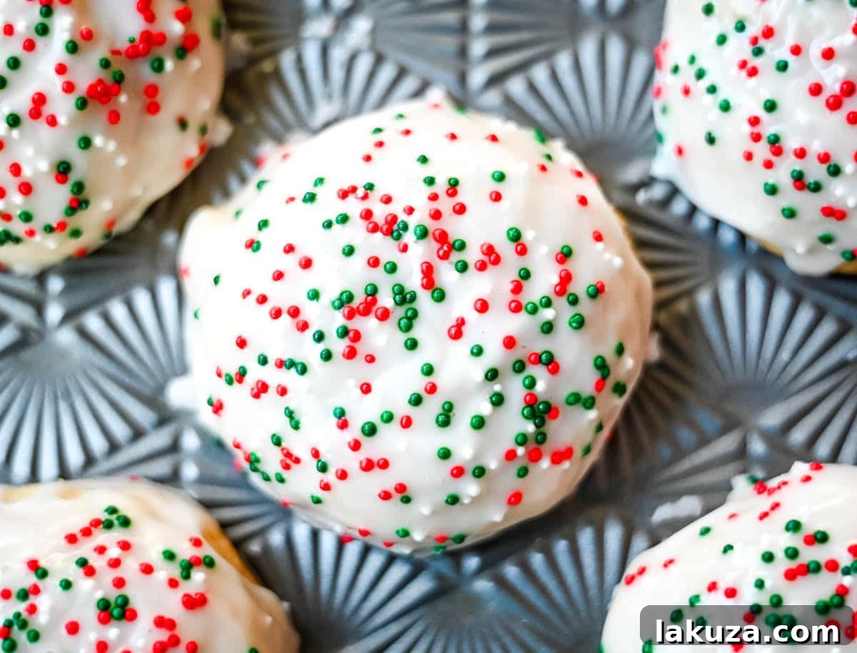 A baking sheet filled with unglazed, freshly baked Italian ricotta cookies cooling, showing their slightly puffed, cakey appearance.