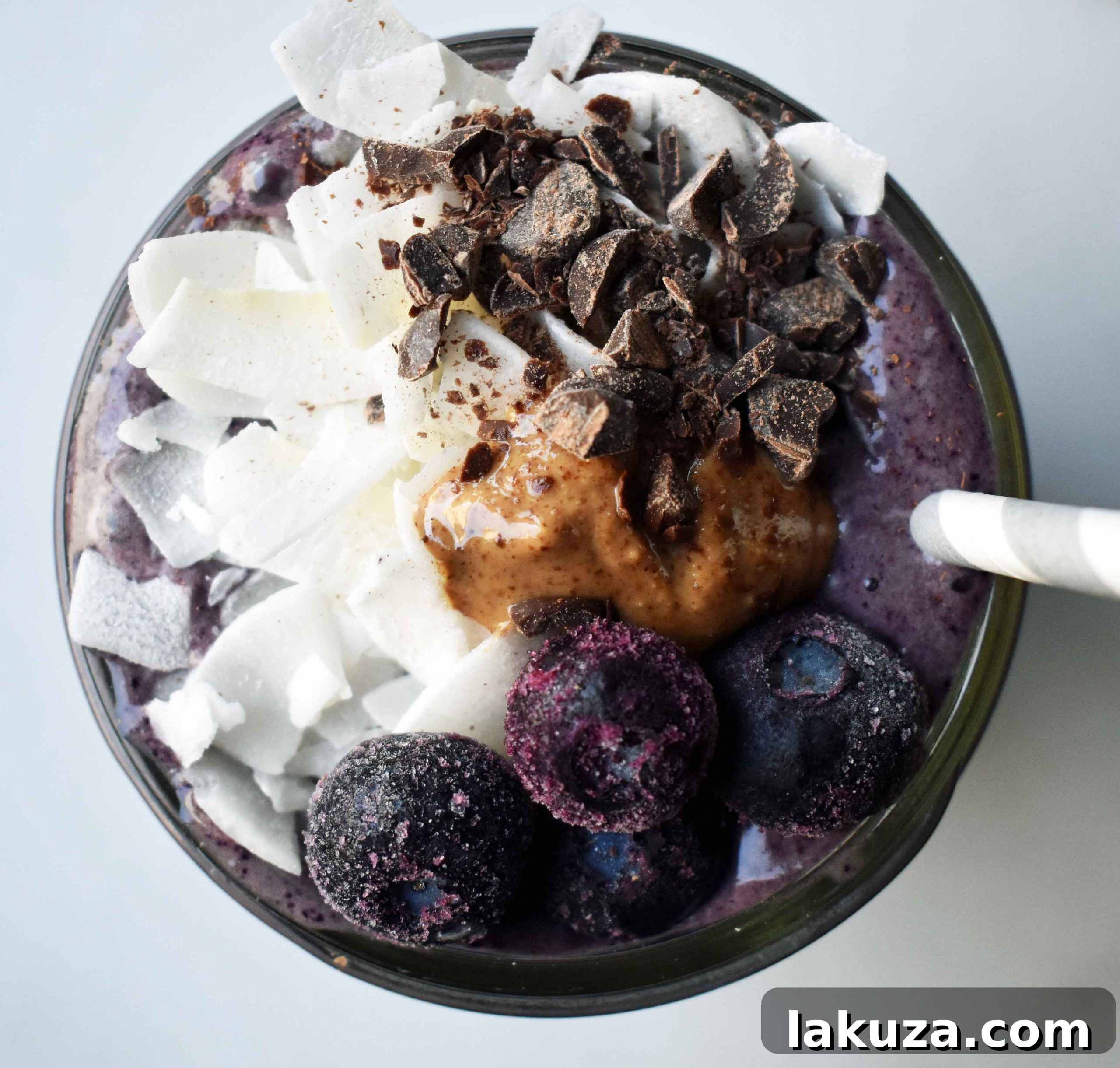 Deep Blue Cacao Dream 3 A close-up of the Wild Blueberry Chocolate Coconut Smoothie, showing its thick, creamy texture and generous toppings of fresh blueberries, swirled almond butter, and delicate dark chocolate shavings. This crave-worthy protein shake is packed with nutrition.