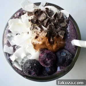 Wild Blueberry Chocolate Coconut Smoothie. Made with chocolate protein powder, coconut milk, blueberries, almond butter, banana, cacao powder. Topped with blueberries, almond butter, and dark chocolate shavings. A craveworthy chocolate coconut protein shake packed with nutrition. www.modernhoney.com