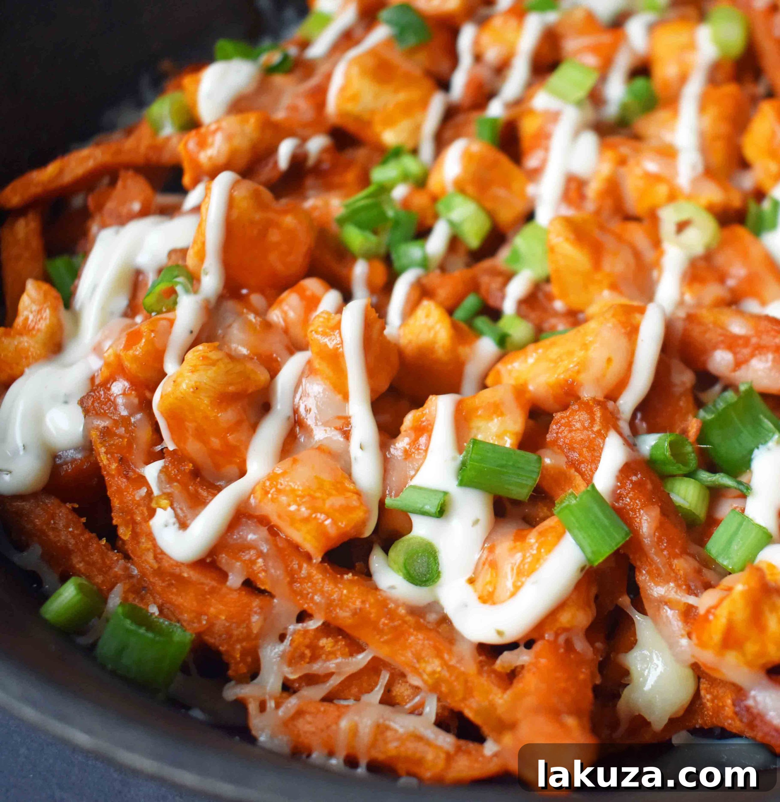 Buffalo Chicken Loaded Sweet Potato Fries 5 Close-up of Buffalo Chicken Sweet Potato Fries by Modern Honey, showcasing crispy fries, buffalo chicken, melted cheese, and fresh garnishes.