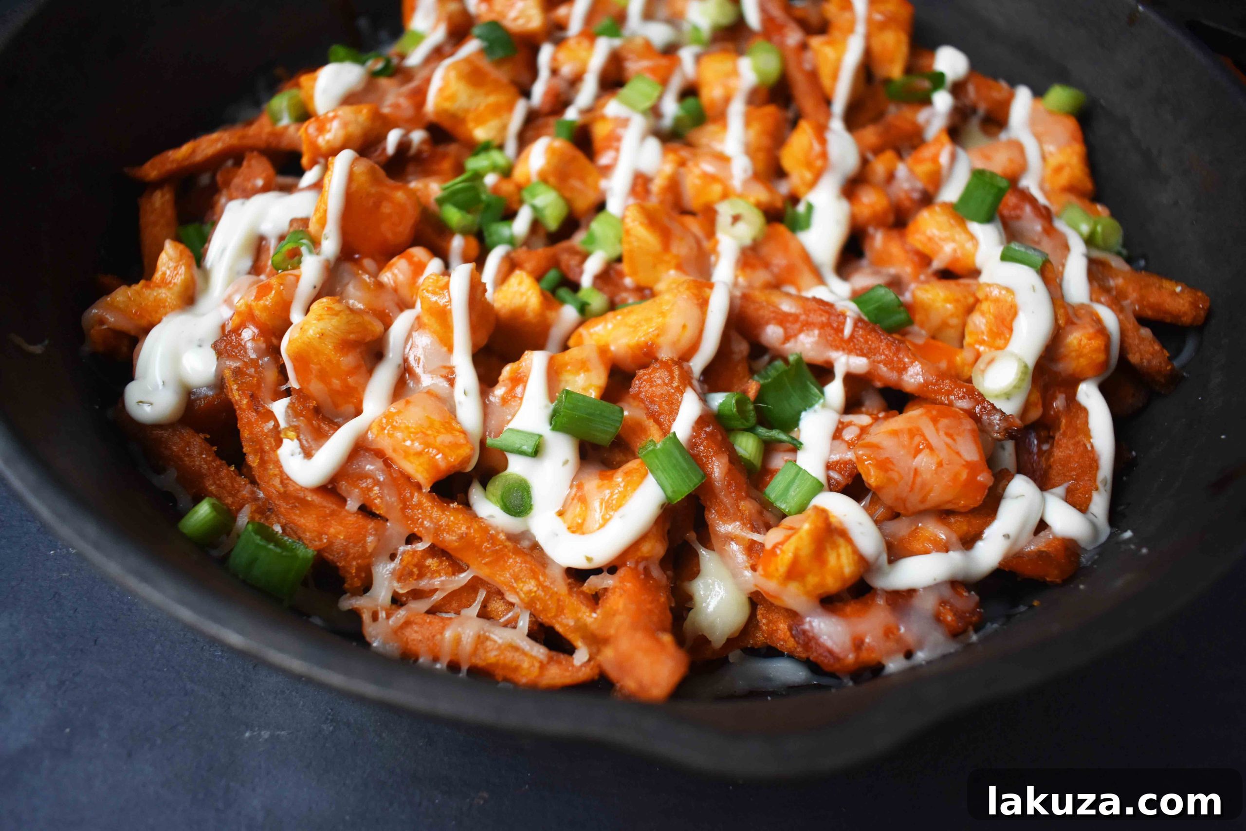 Buffalo Chicken Loaded Sweet Potato Fries 6 Buffalo Chicken Sweet Potato Fries garnished with green onions and ranch dressing, ready to serve.