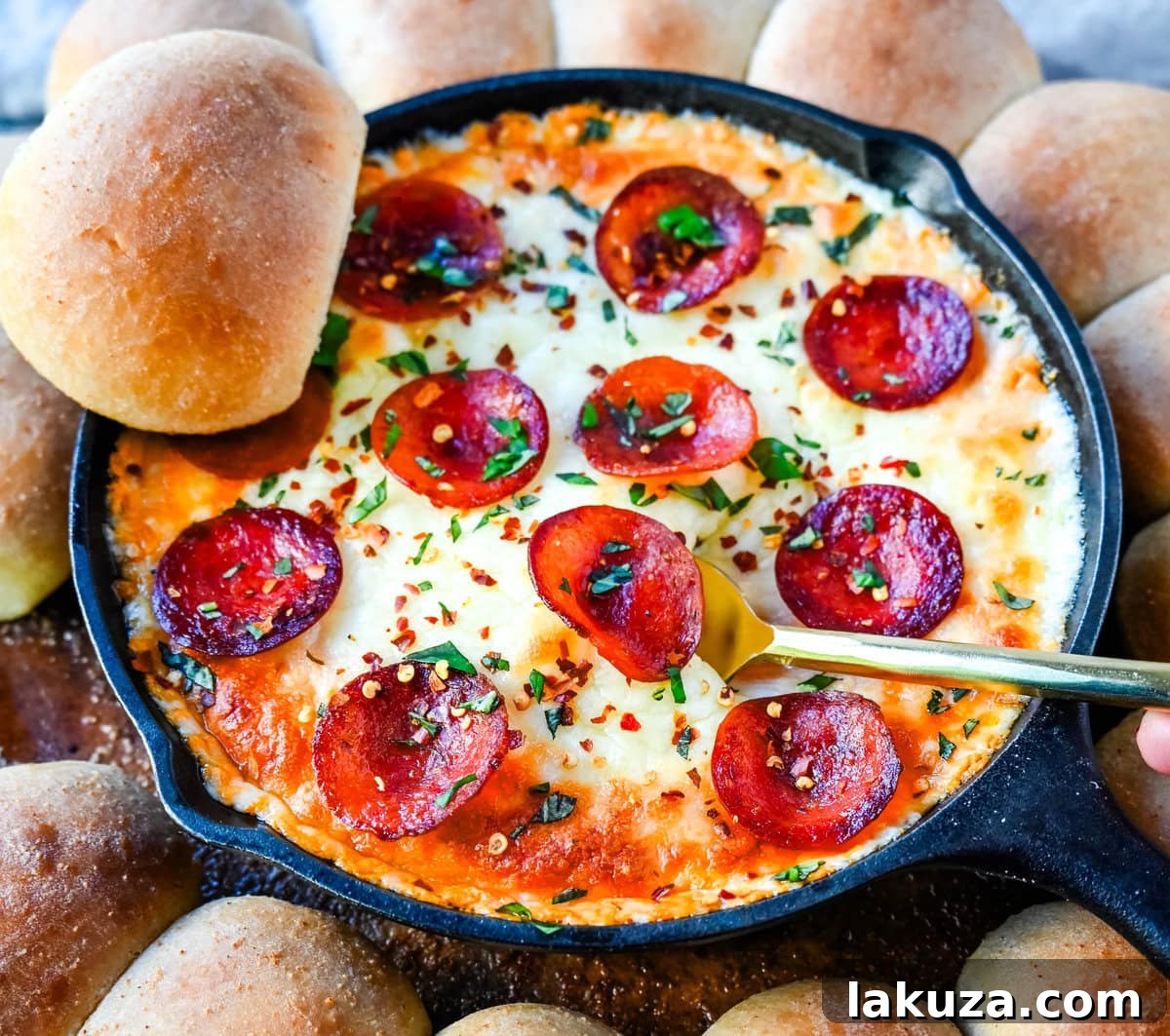 A close-up of a serving of Pepperoni Pizza Dip with a dipper, showing the rich, melted cheese and pepperoni texture.