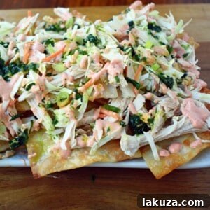 Asian Wonton Chicken Nachos. Fried wontons, pulled chicken, sriracha cream, cabbage mix, and sweet cilantro sauce. An Asian twist on nachos for the perfect party appetizer.