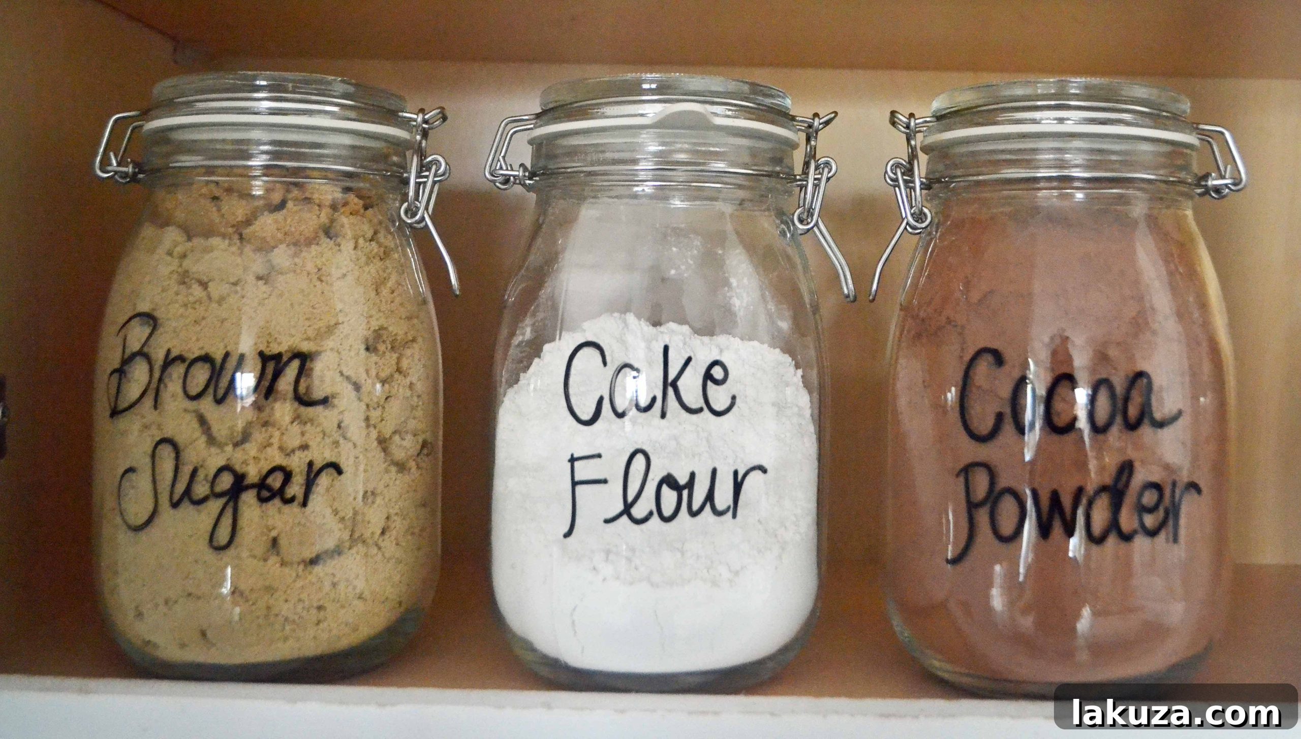 Close-up view of baking ingredients stored in glass jars on shelves, emphasizing labels and accessibility.