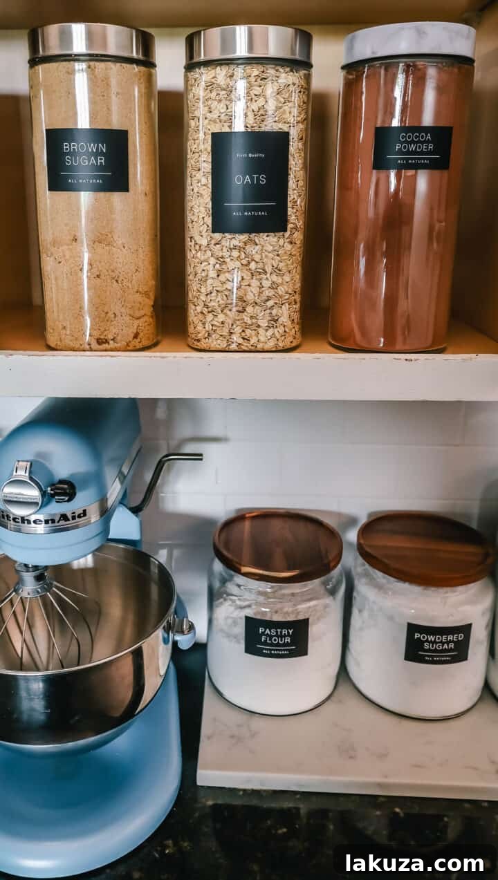 An organized kitchen cabinet showcasing a variety of baking ingredients in labeled glass jars, making everything easy to find.