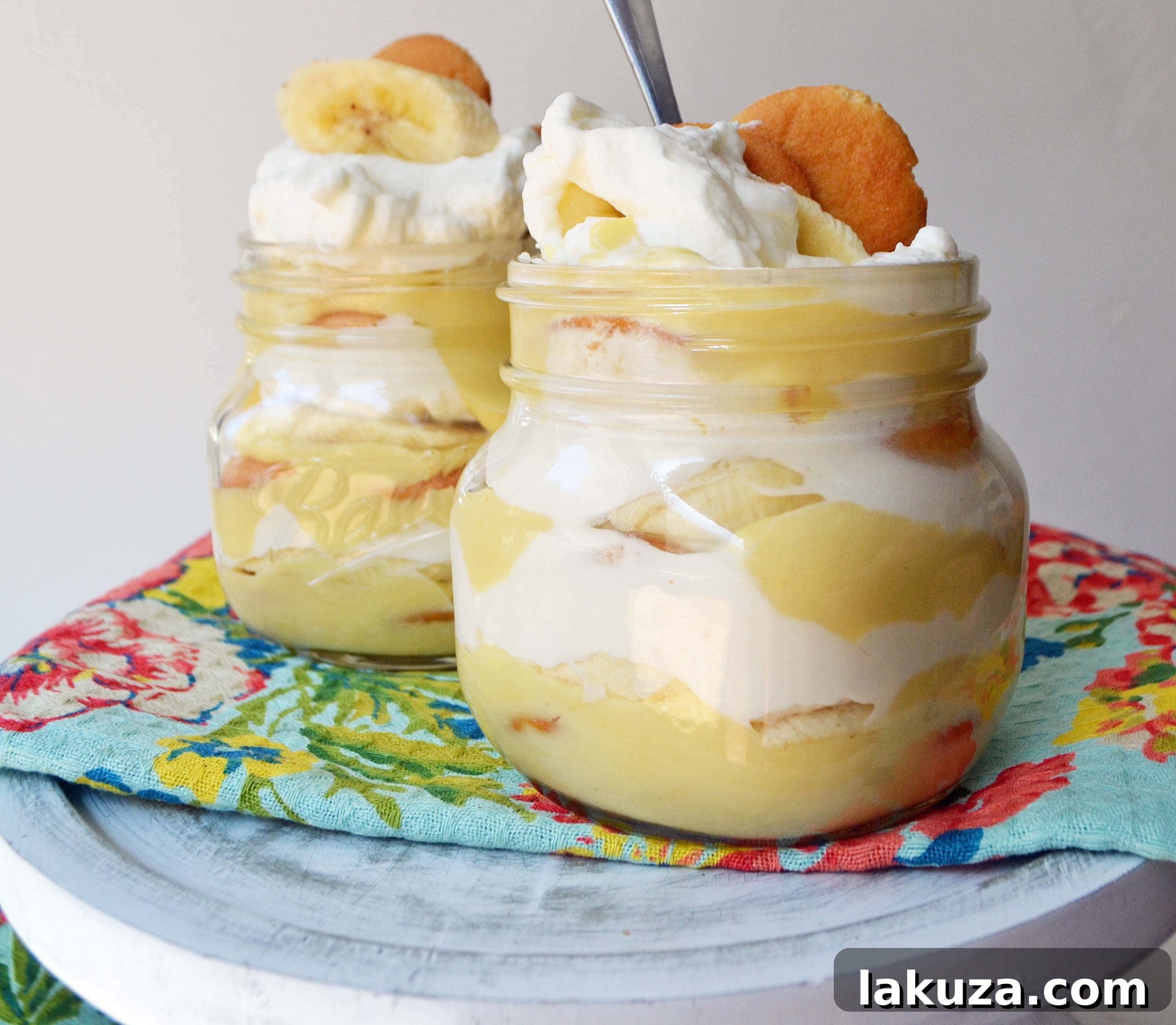 Layered Homemade Banana Pudding Dessert Recipe. Features creamy vanilla bean custard, fresh banana slices, classic Nilla wafers, and a generous topping of whipped cream, presented in a clear glass dish, perfect for sharing or individual servings. A comforting and delicious Southern dessert.