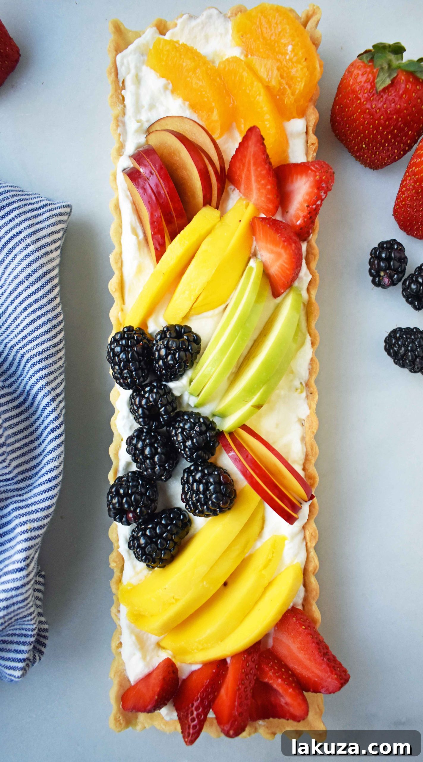 A close-up, high-angle shot of a bountiful Fresh Fruit Tart, emphasizing the glossy glaze and plump berries.