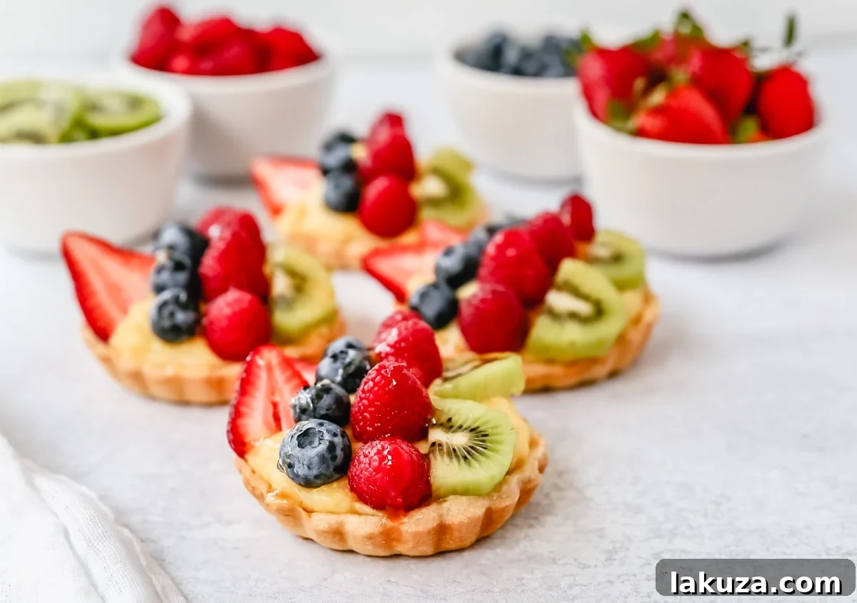 Close-up of a fruit tart slice revealing layers of golden crust, creamy vanilla pastry cream, and juicy fresh berries.