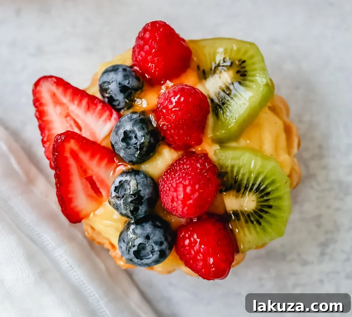 Overhead view of a beautifully arranged fruit tart with a variety of fresh seasonal fruits on vanilla custard.