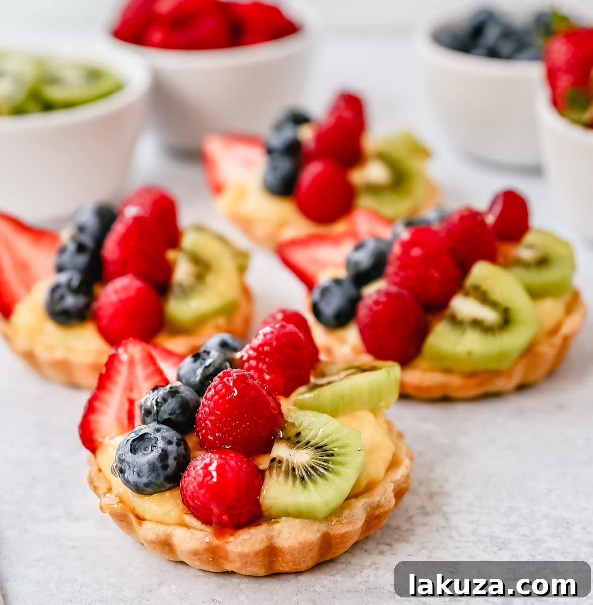 A beautifully decorated French fruit tart, cut into a slice, revealing layers of crust, vanilla cream, and colorful berries.