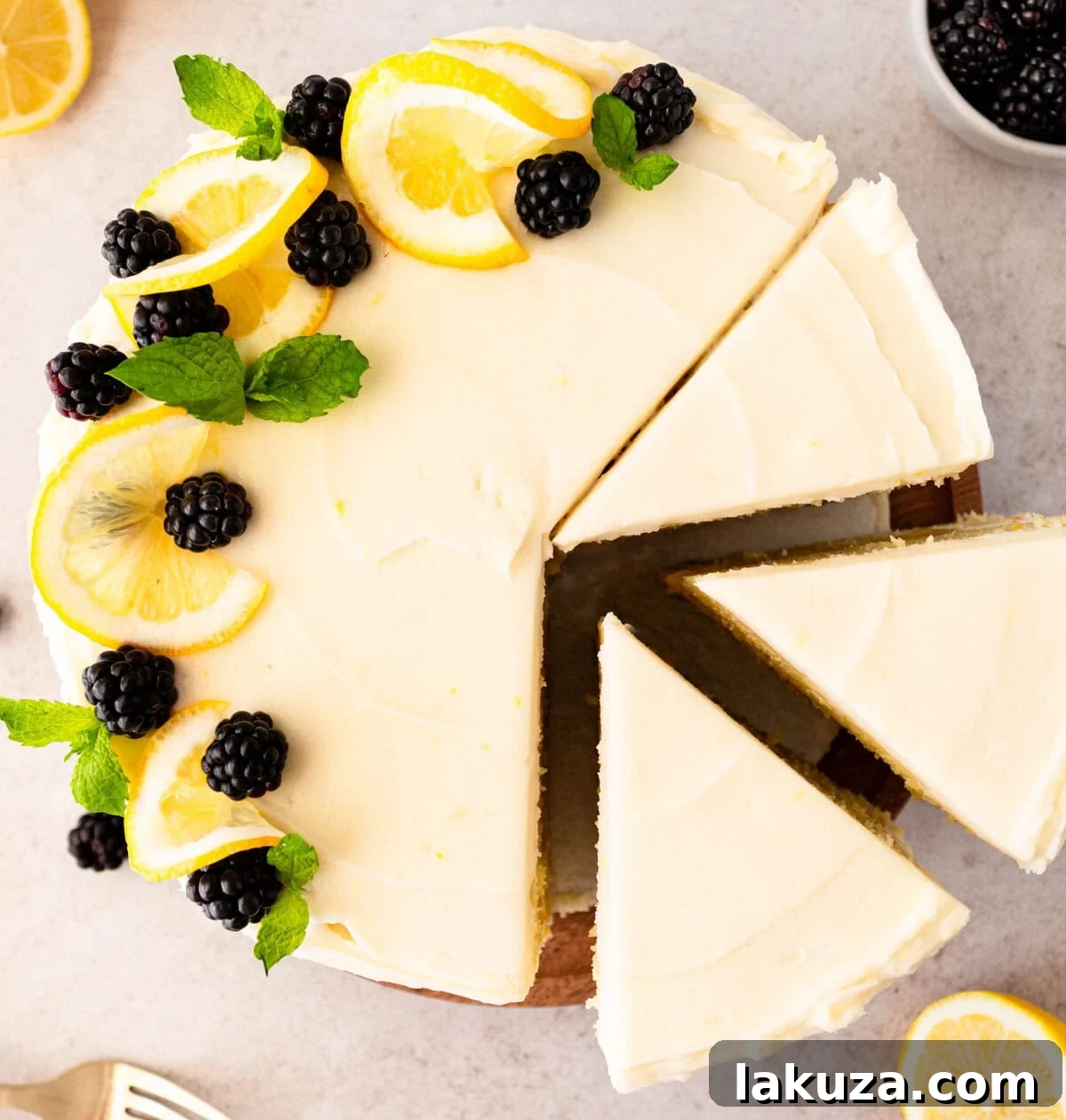 A stunning two-layer Italian Lemon Olive Oil Cake, fully frosted with lemon cream cheese and garnished with fresh blackberries and lemon zest.