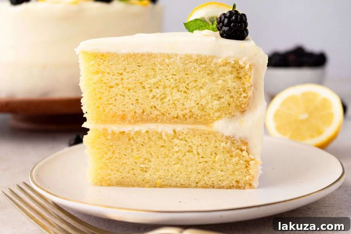 A close-up shot of a perfectly frosted Lemon Olive Oil Cake slice, showcasing the creamy texture and fresh garnish.