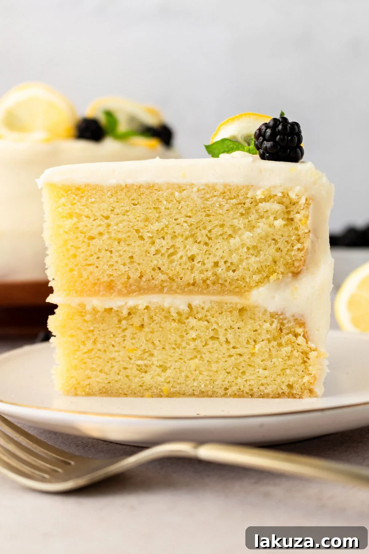 Several slices of Lemon Olive Oil Cake with thick cream cheese frosting, garnished with fresh mint and lemon slices, ready to be served.