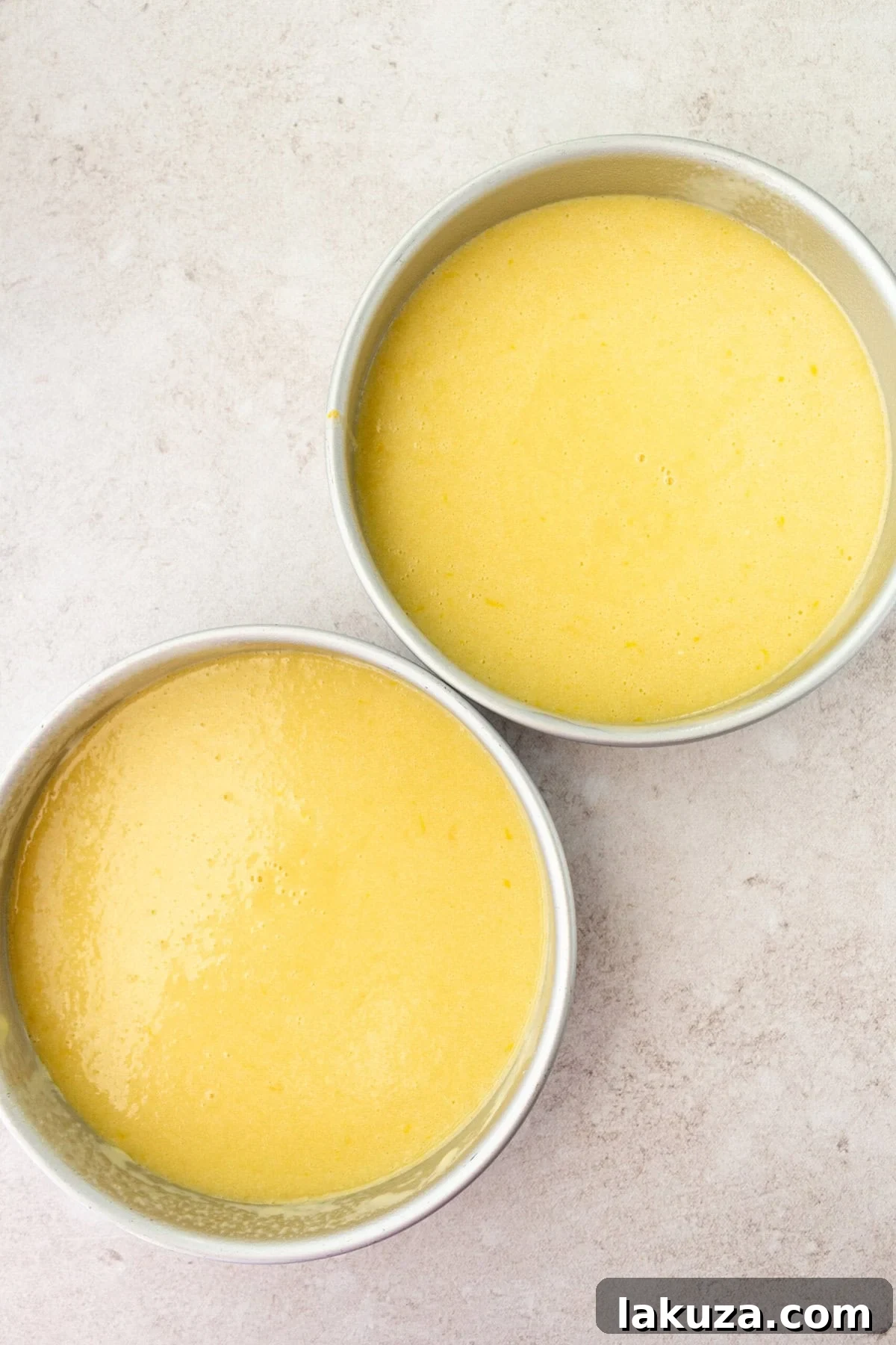 Lemon Olive Oil Cake batter perfectly poured into two 9-inch round cake pans, ready for baking.