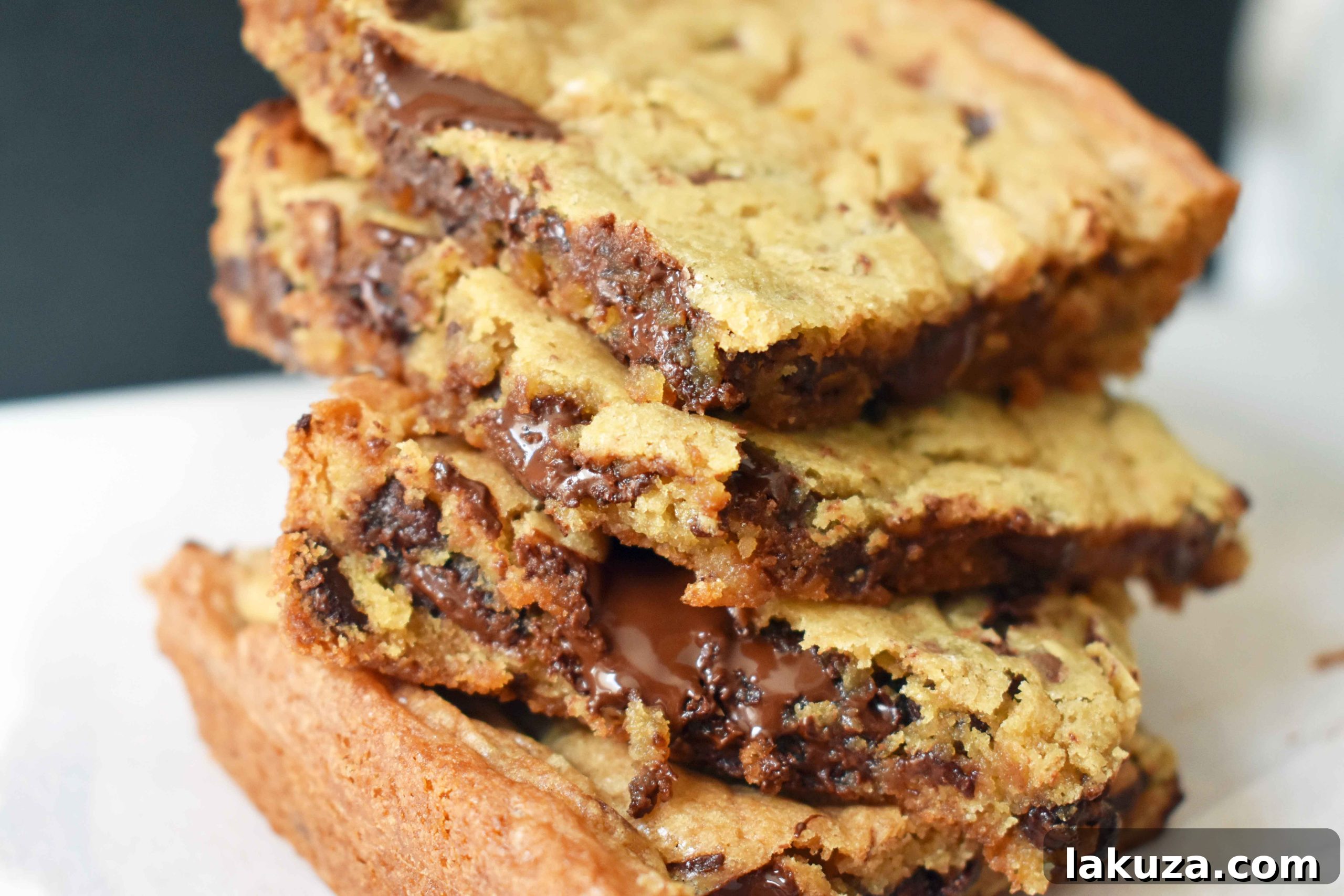 Irresistible Chocolate Chip Bars 5 A stack of freshly baked chocolate chip cookie bars on a cooling rack, with more in the background, ready to be enjoyed.