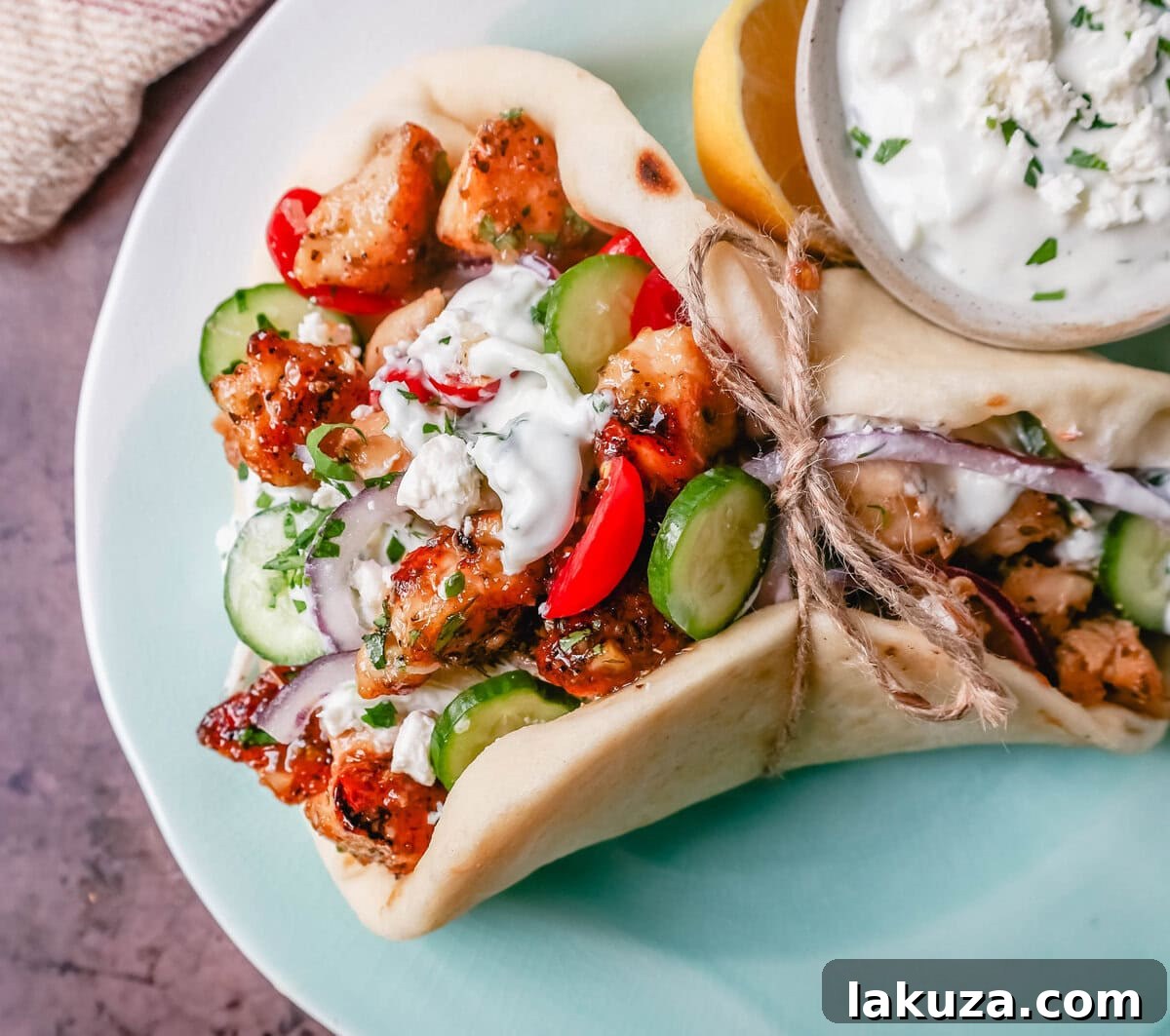 Platter of freshly made Greek Chicken Gyros with homemade tzatziki sauce, fresh Greek salad, and soft pita bread ready to serve.