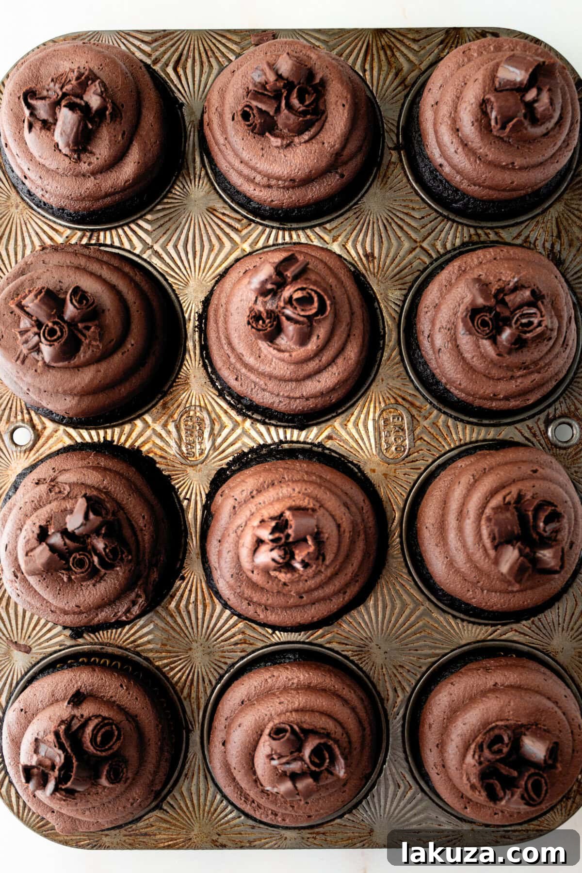 Decadent Chocolate Cupcakes 12 A stunning spread of finished chocolate cupcakes, richly frosted and adorned with various chocolate garnishes, arranged enticingly.