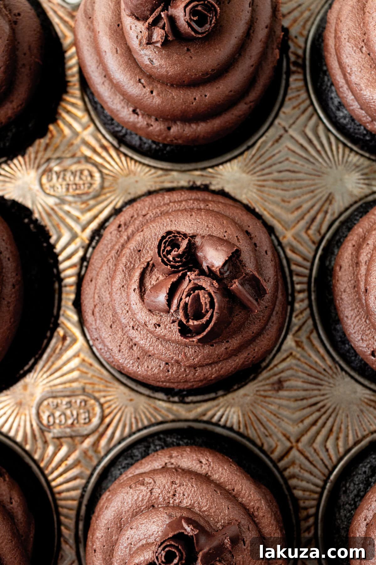 Decadent Chocolate Cupcakes 7 A close-up of a generously frosted chocolate cupcake, beautifully decorated with chocolate shavings, highlighting the creamy texture of the buttercream.