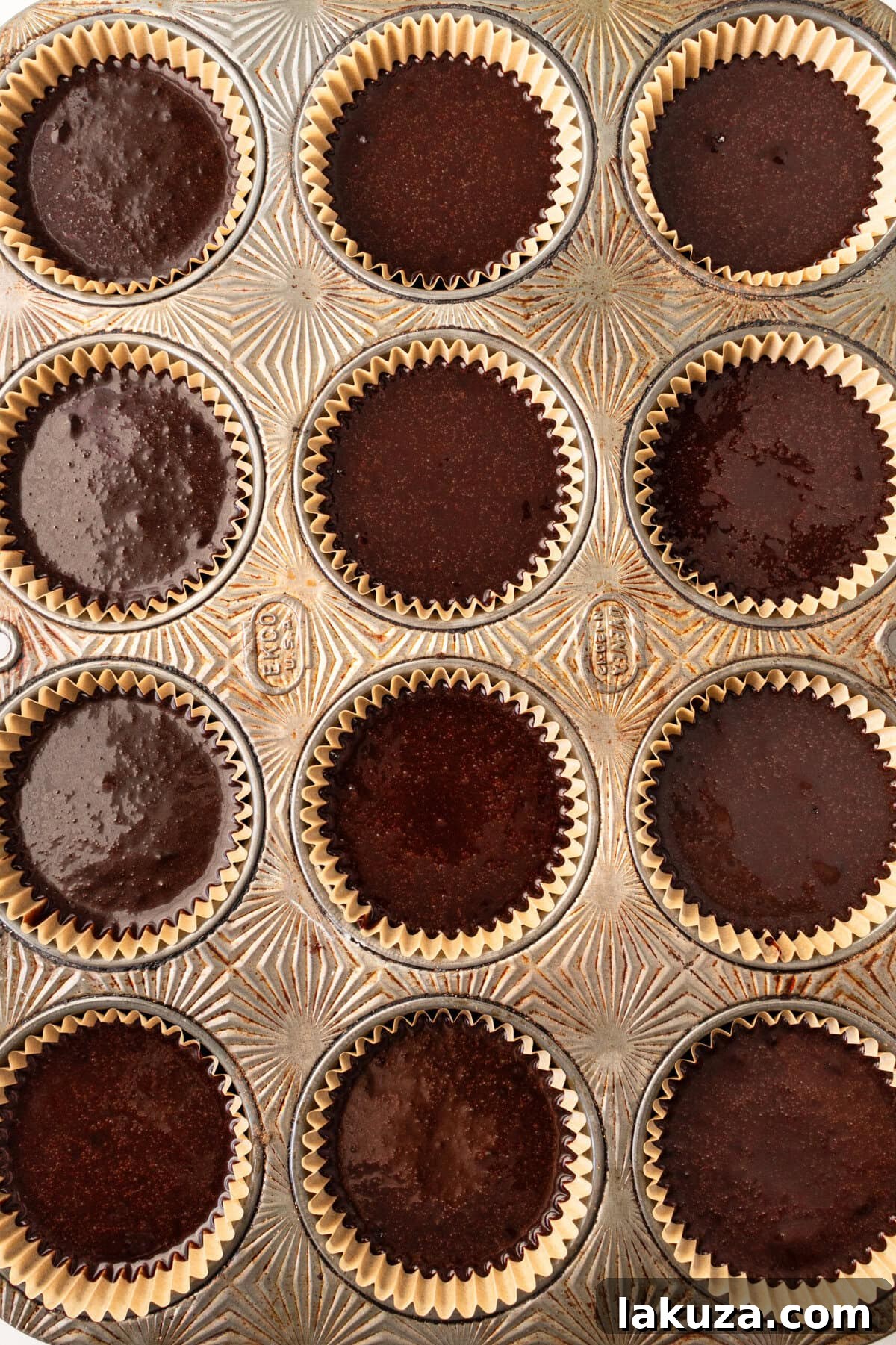 Decadent Chocolate Cupcakes 10 Chocolate cupcake batter neatly portioned into cupcake liners within a muffin tin, ready for baking.