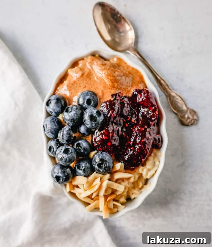 Craft Your Oat Creation 3 Oatmeal topped with almond butter, berry jam, and slivered almonds, showcasing a rich and flavorful breakfast.