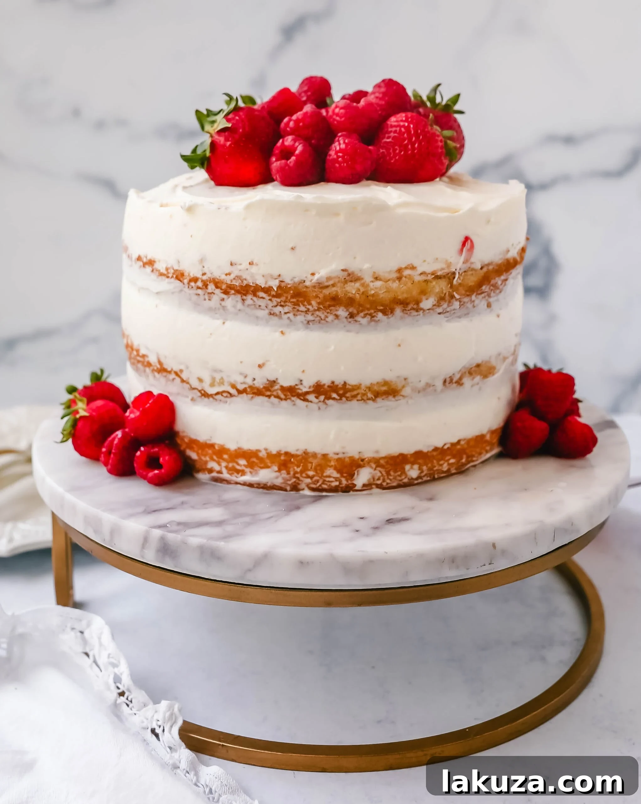 Berry Chantilly Cake 15 A slice of homemade yellow cake with fluffy cream cheese whipped cream frosting and vibrant fresh berries on a plate.