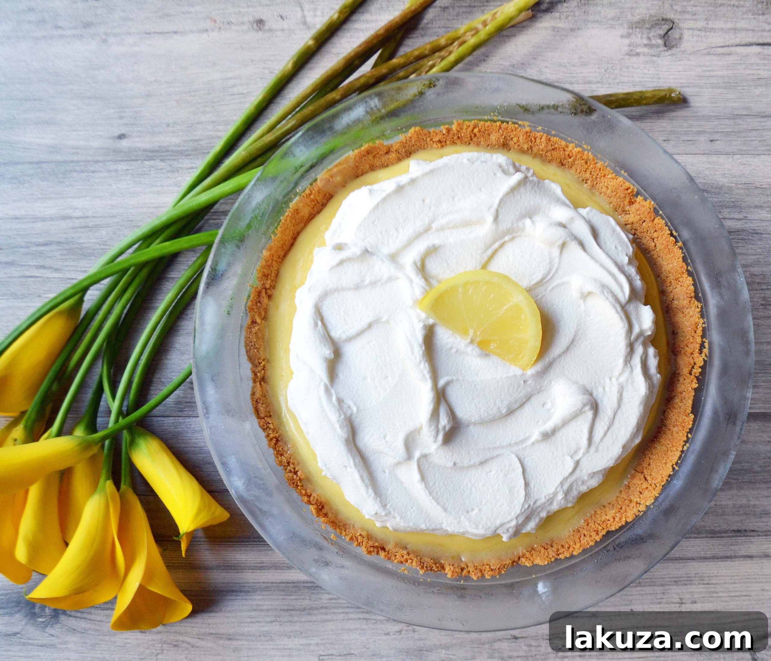 Sunshine Lemon Parfait Jars 7 A beautifully sliced Lemon Cream Pie, showing its distinct layers of golden crust, creamy lemon filling, and fluffy white topping, garnished with fresh lemon and mint.