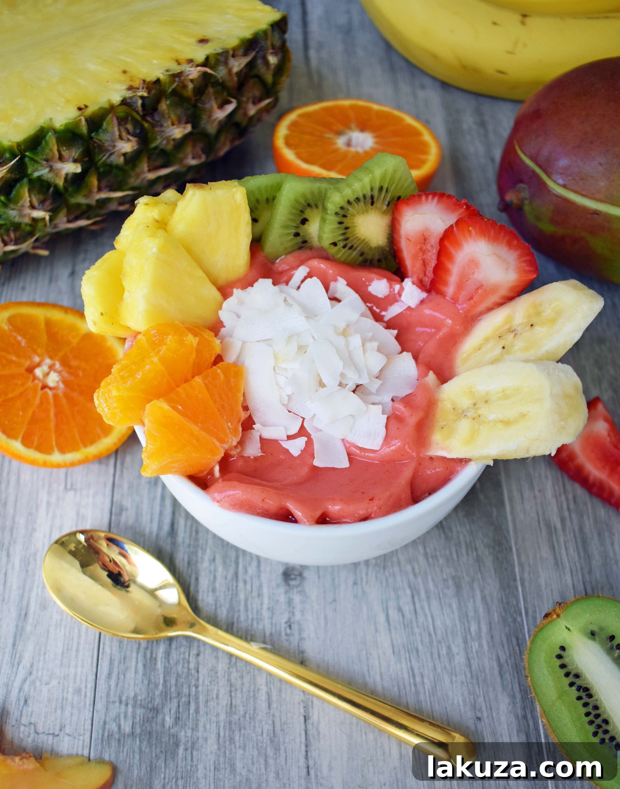 Kissed by Sunshine Smoothie Bowl made with frozen fruits, juice or coconut milk, and topped with fresh fruits, coconut shavings, and granola. A healthy and filling breakfast. www.modernhoney.com