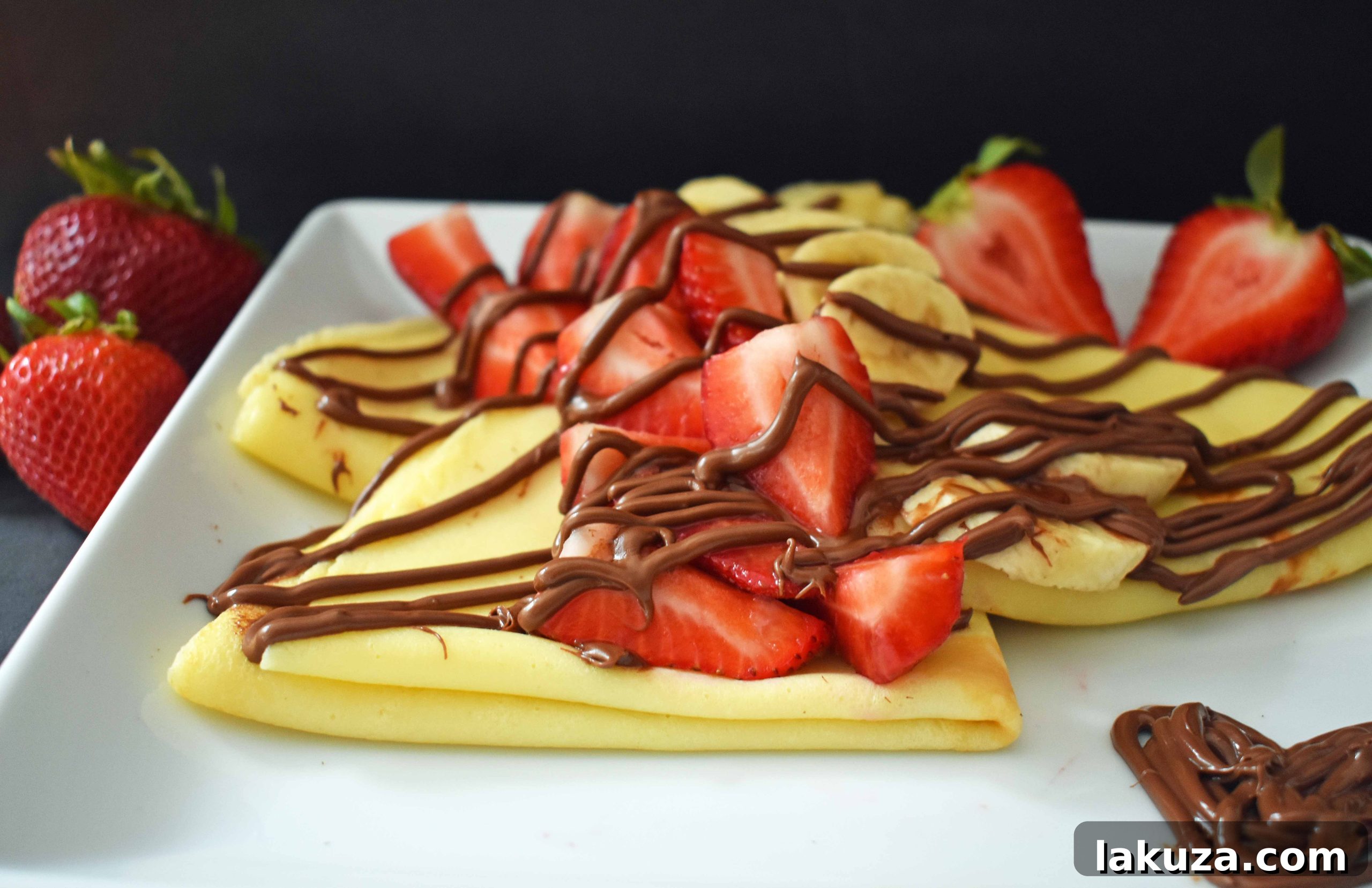 Stack of freshly made crepes with a dusting of powdered sugar, ready for toppings. Modern Honey.