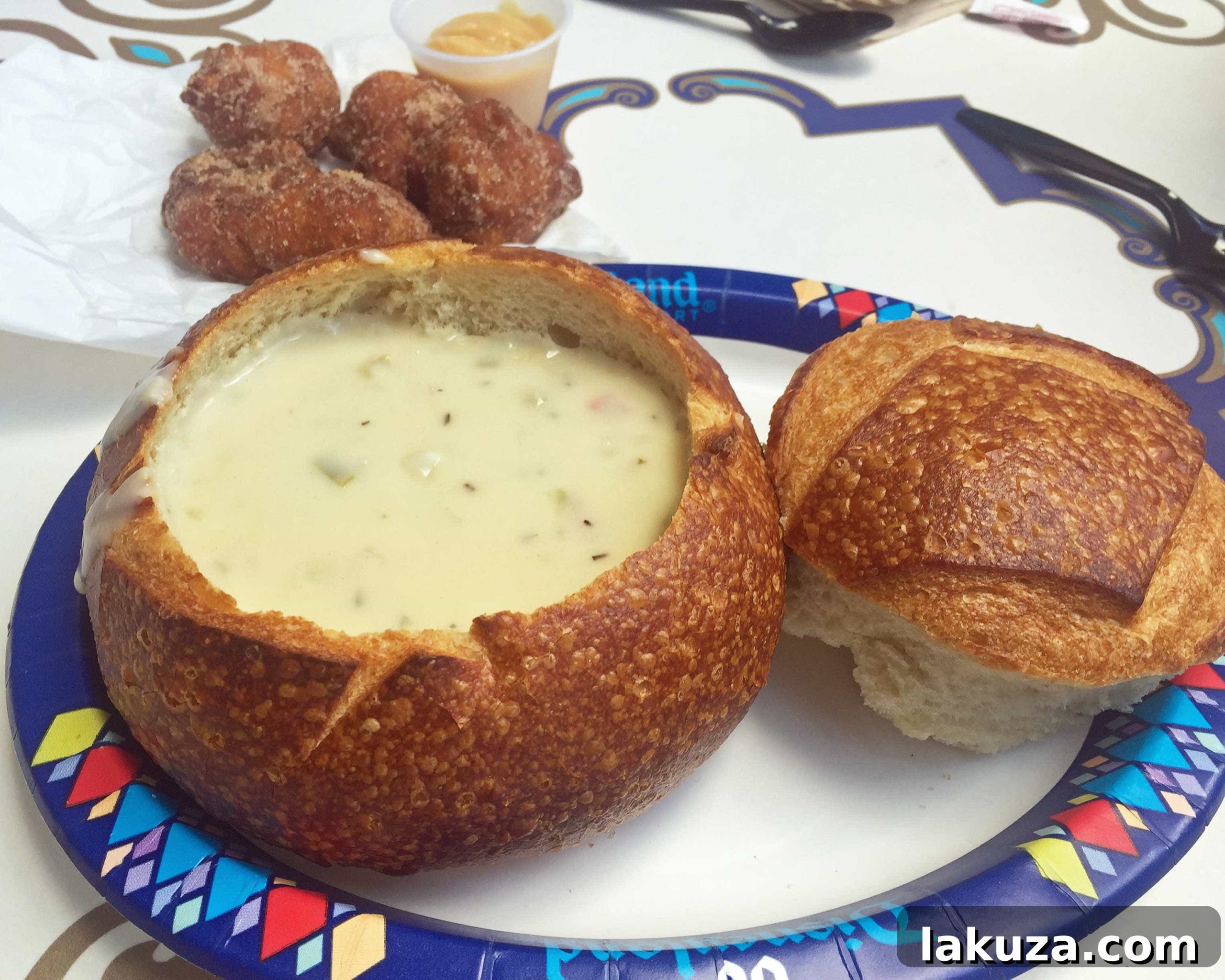 Disneyland's Gastronomic Gold: Essential Eats & Sweet Treats 15 New Orleans Fritters and Clam Chowder in a Sourdough Bread Bowl at Royal Street Veranda in Disneyland, offering both sweet and savory delights.