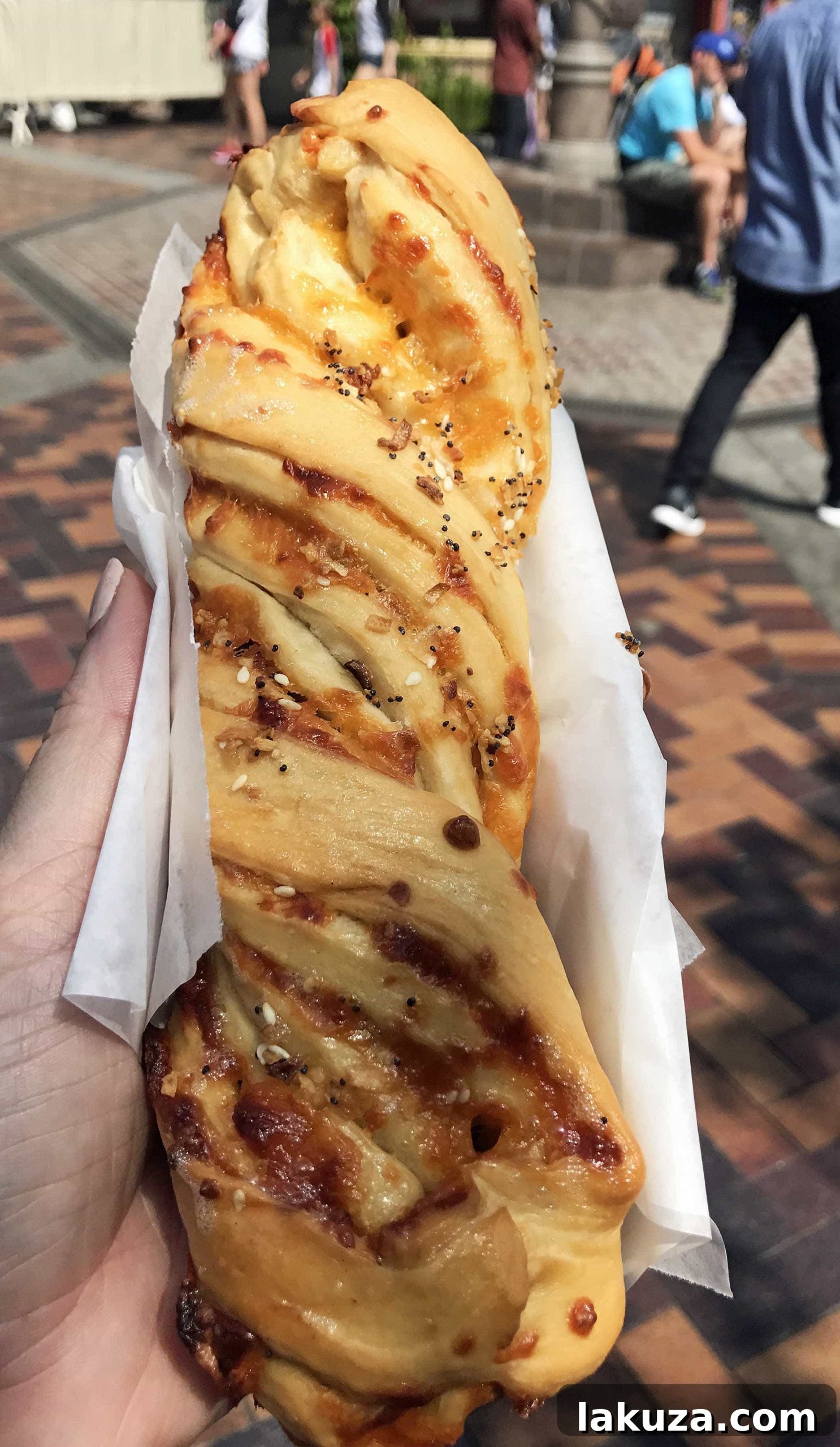 Disneyland's Gastronomic Gold: Essential Eats & Sweet Treats 7 The savory Cheddar Garlic Bagel Twist at Disneyland's Maurice's Treats, a large, cheesy, and garlicky snack perfect for breakfast or a quick bite.