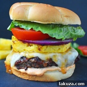 Sweet and Spicy Hawaiian Burger made with grass-fed beef grilled to perfection and basted with a Hawaiian pineapple sauce and topped with melted Swiss Cheese. It is put on a warm toasted bun covered in Sriracha mayonnaise and topped with grilled pineapple, lettuce, tomato and red onion. A sweet and spicy burger that makes you think you are sitting on a beach in Hawaii! www.modernhoney.com
