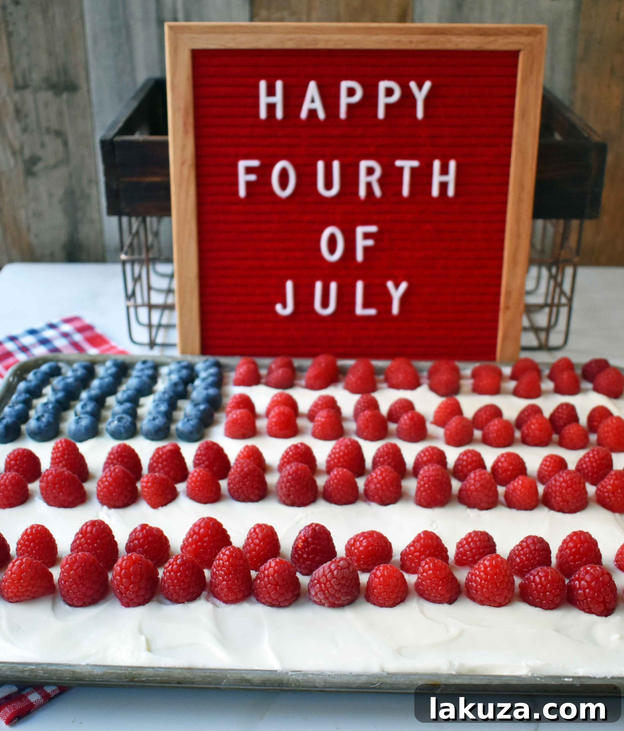 Southern Charm Vanilla Sheet Cake 8 A large White Texas Sheet Cake covered in almond cream cheese frosting with a portion decorated with raspberries and blueberries in a flag design.