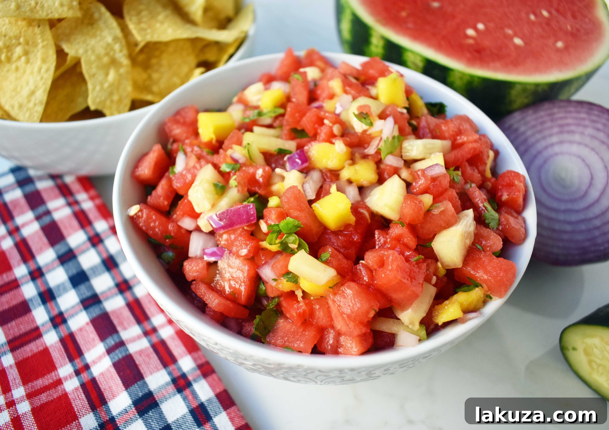 A bowl of fresh Watermelon Mango Salsa, garnished with cilantro, ready to be served. The vibrant colors of red, orange, and green are prominently displayed.