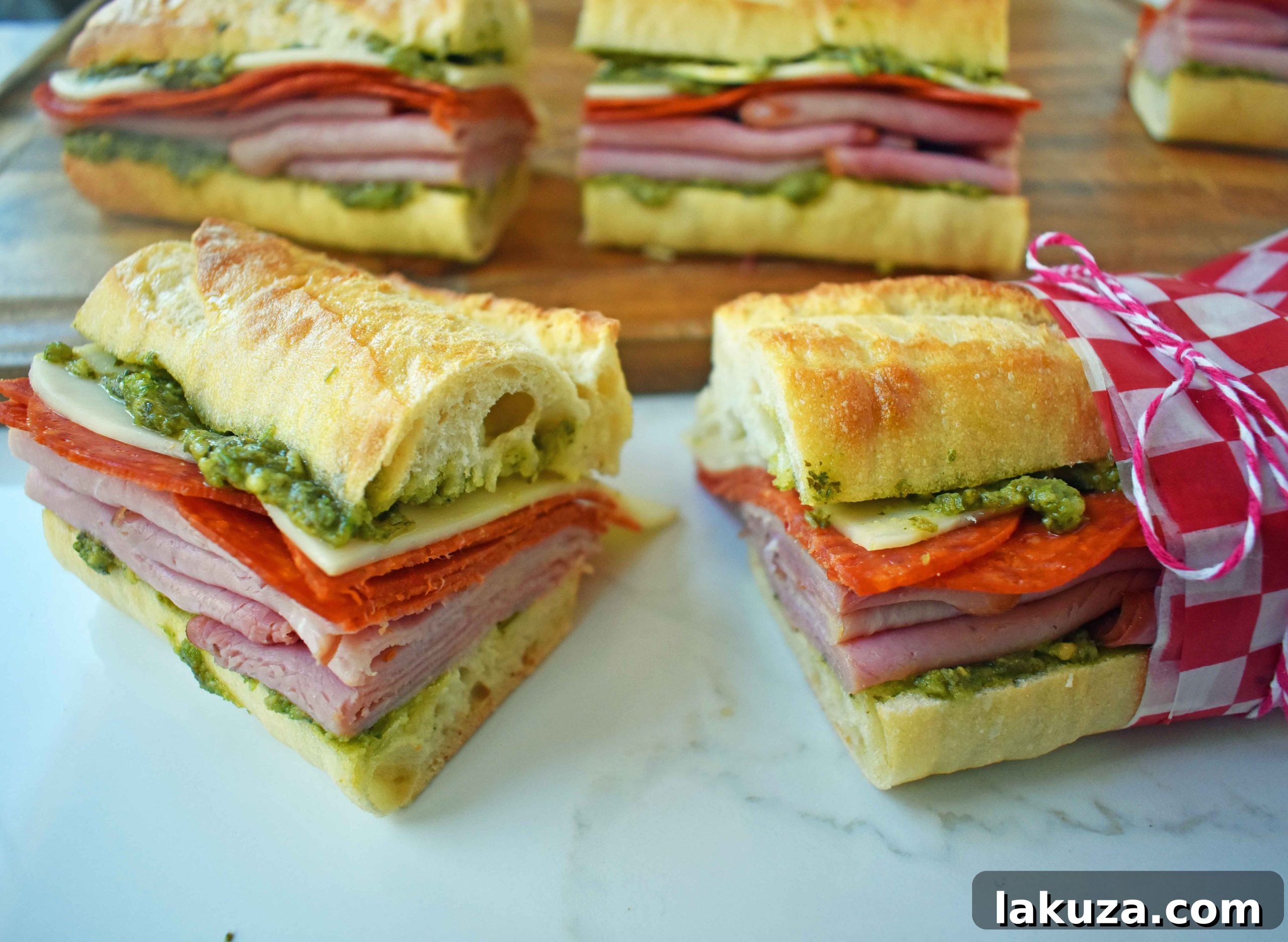 Rustic Italian Pressed Sandwich with layered meats, cheeses, pesto, and marinated tomatoes on French bread