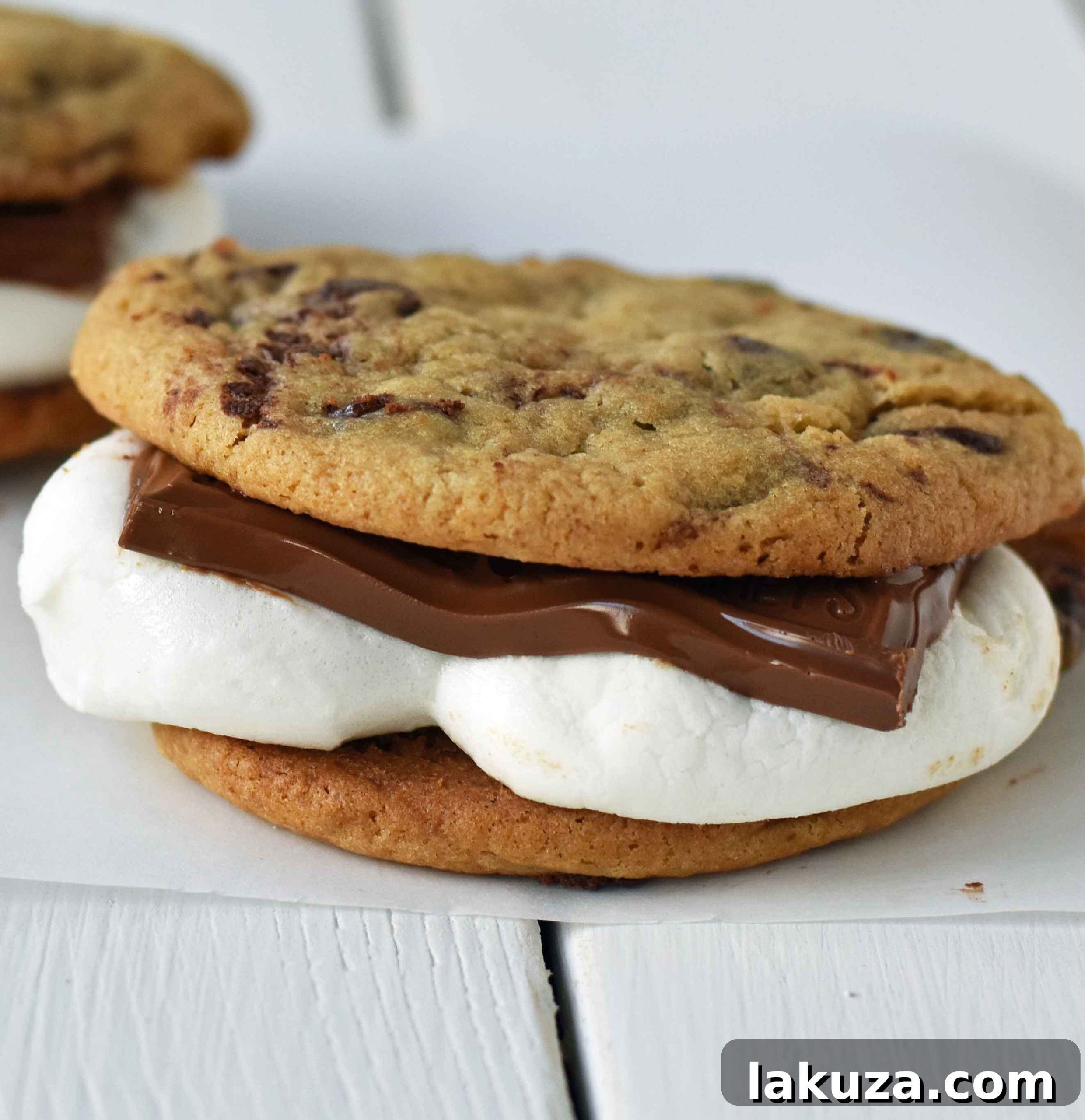Ultimate S'mores Chocolate Chip Cookies 5 A perfectly layered Chocolate Chip Cookie S'more, showcasing the distinct layers of cookie, toasted marshmallow, and melted chocolate, ready to be eaten.