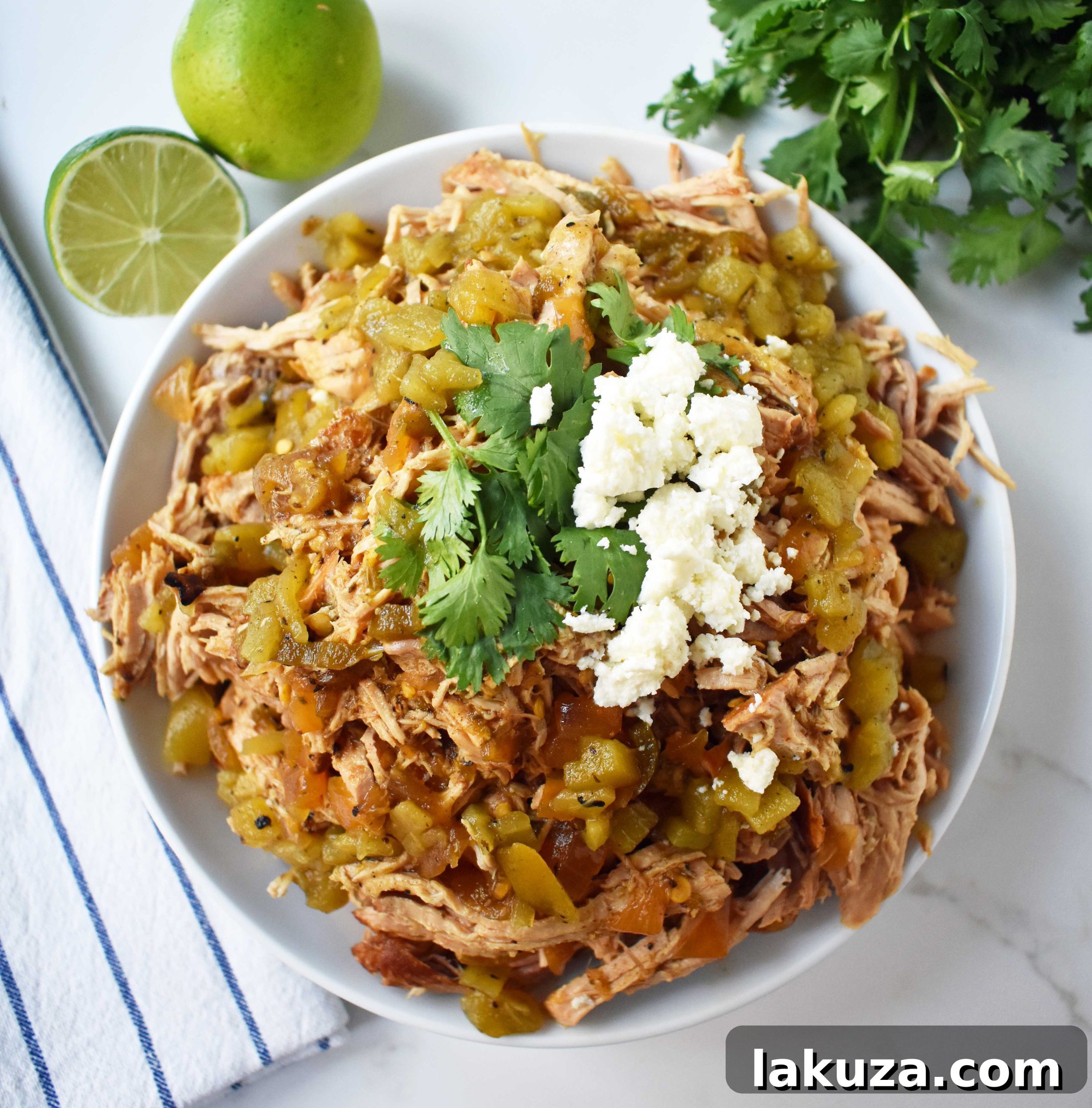 A vibrant platter of Green Chili Pork Carnitas Tacos ingredients, highlighting the shredded slow-cooked pork, fresh avocado, cilantro, and crumbled cotija cheese, ready for assembly.