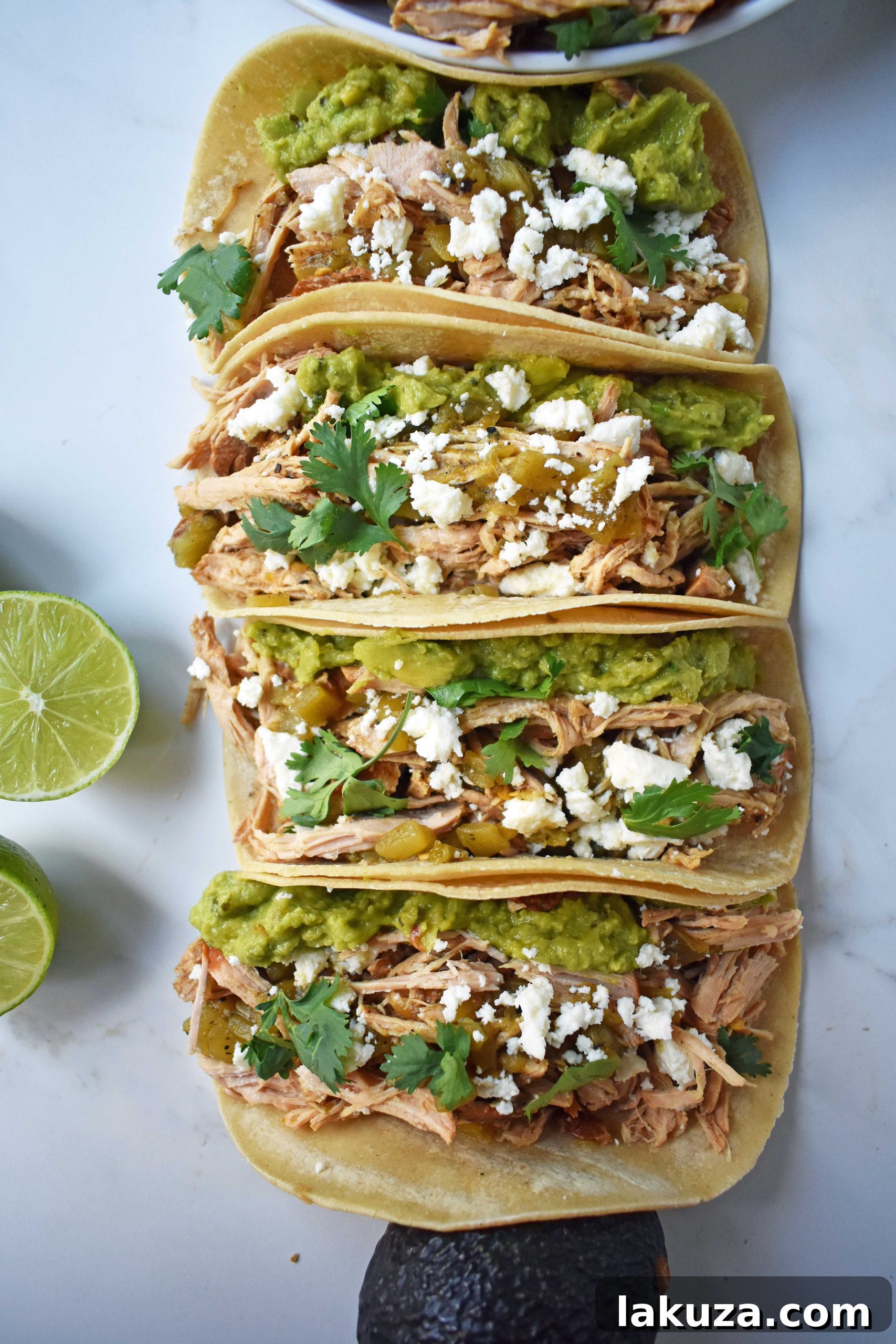 A beautifully presented Green Chili Pork Carnitas Taco, showcasing the succulent pork, vibrant green chili sauce, creamy guacamole, fresh cilantro, and crumbled cotija cheese, ready to be enjoyed.