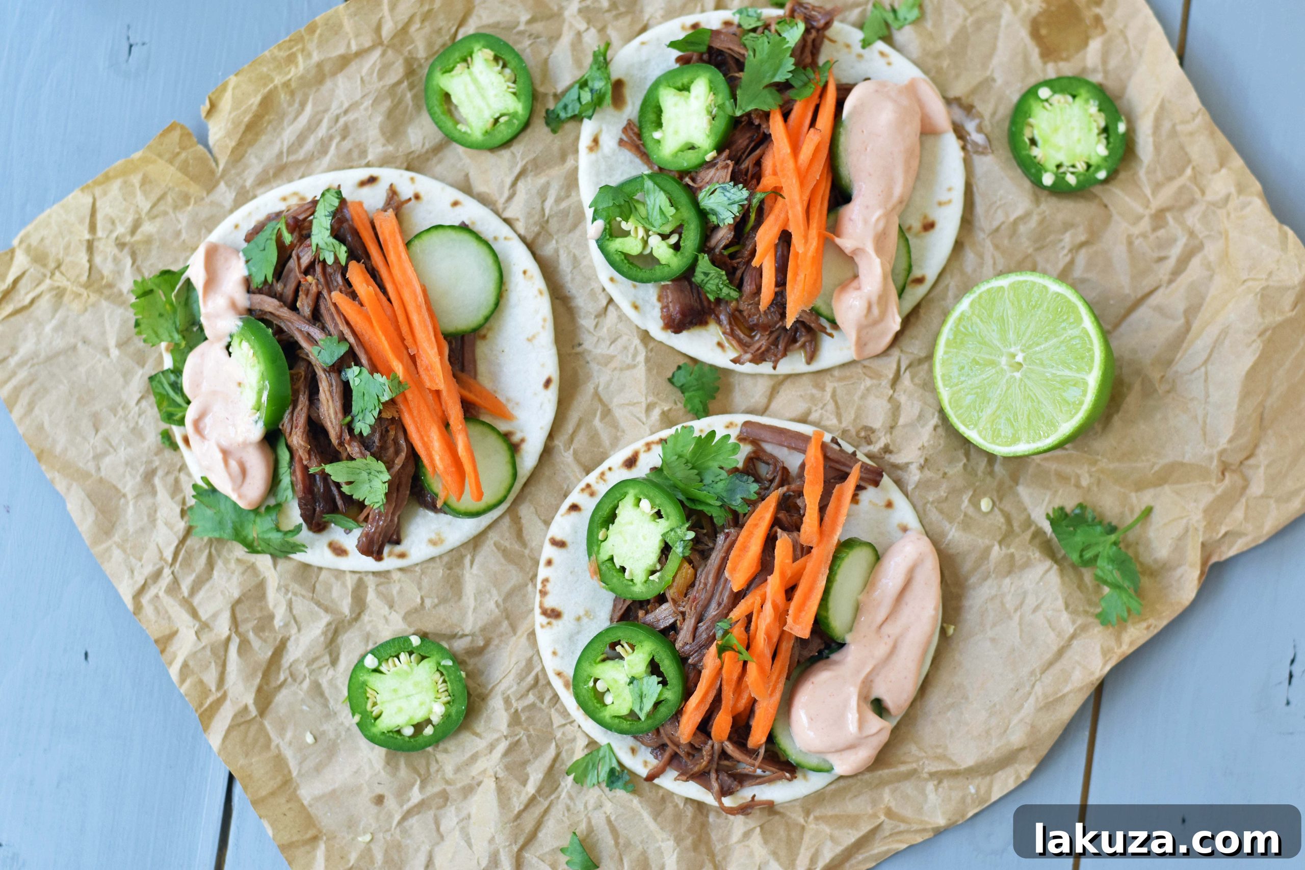 Shredded Korean Beef Tacos topped with fresh vegetables and sriracha cream