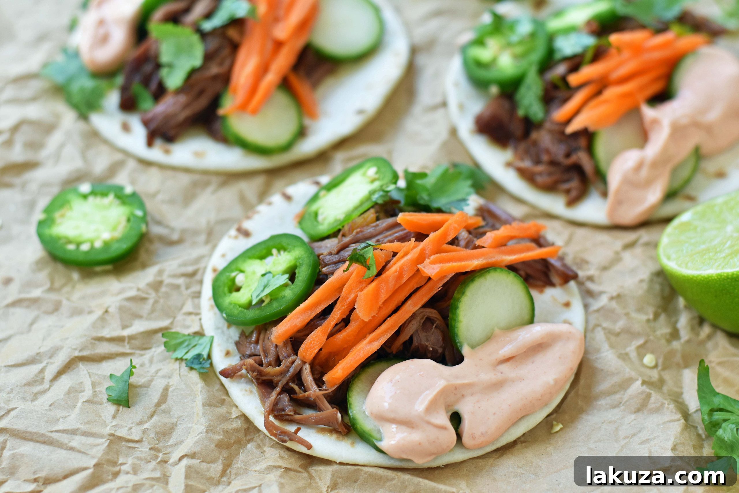 Close-up of Slow Cooker Korean Beef Tacos garnished with cilantro and sriracha drizzle