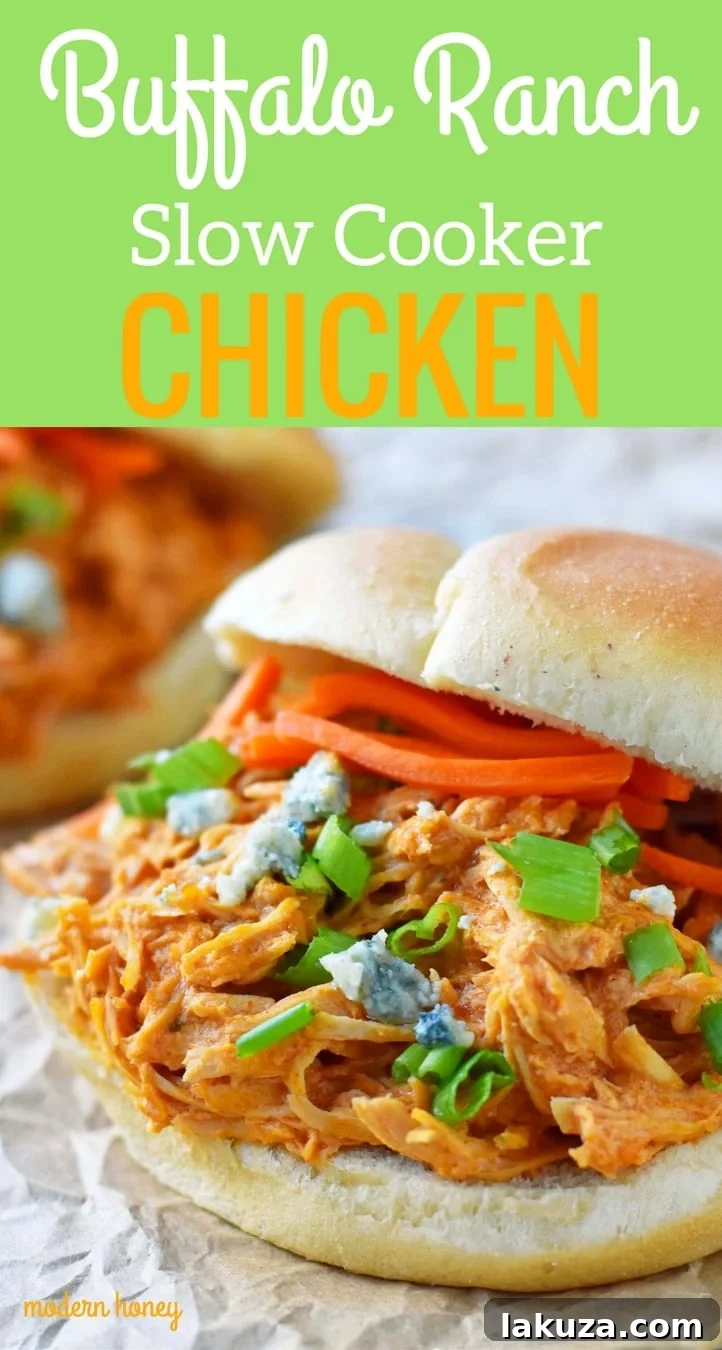 Zesty Creamy Slow Cooker Buffalo Ranch Chicken 6 Closeup shot of Buffalo Ranch Slow Cooker Chicken served on a brioche slider bun, topped with blue cheese crumbles and matchstick carrots, ready for a game day party. The shredded chicken is visibly moist and coated in creamy, tangy sauce.