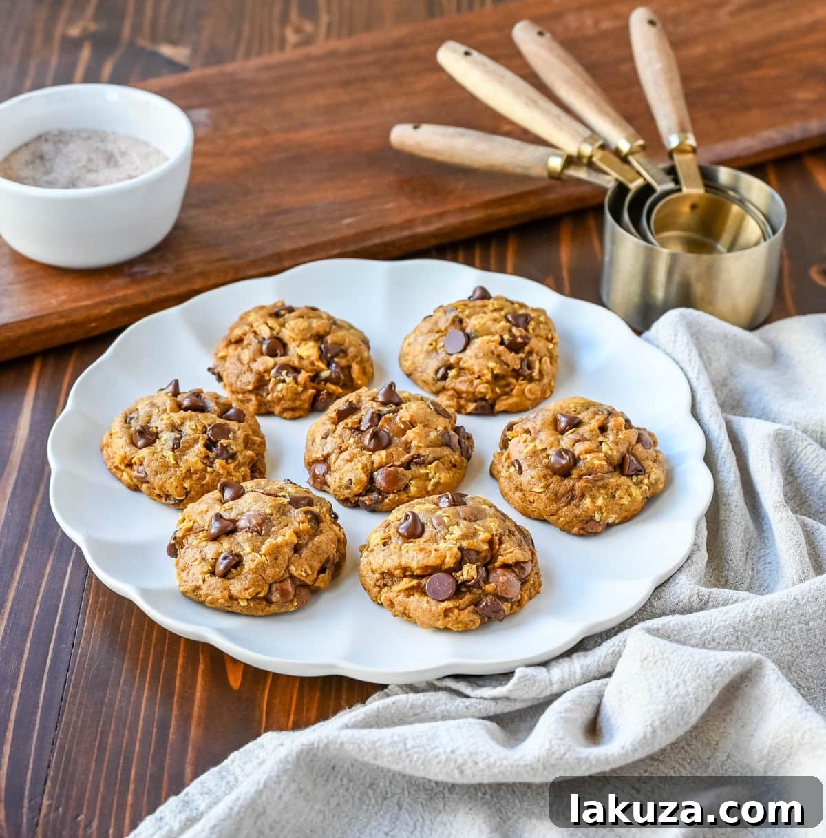 A stack of golden-brown Pumpkin Oatmeal Chocolate Chip Cookies, revealing their texture and the generous amount of chocolate chips, set against a warm, autumnal background.