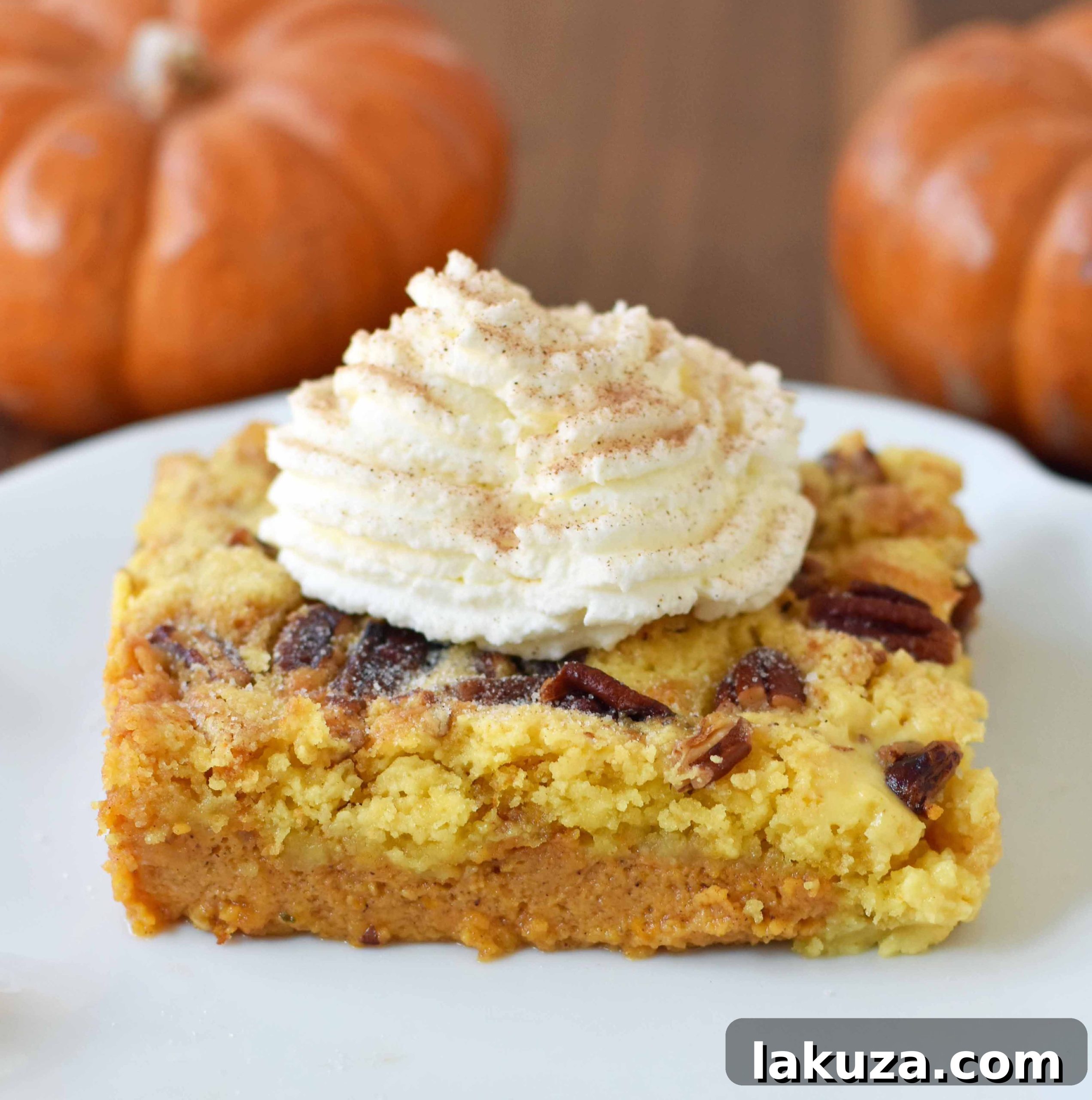 Close-up of a slice of Pumpkin Praline Butter Dump Cake, revealing the creamy pumpkin layer and the golden, crunchy, buttery pecan praline topping. Modernhoney.com