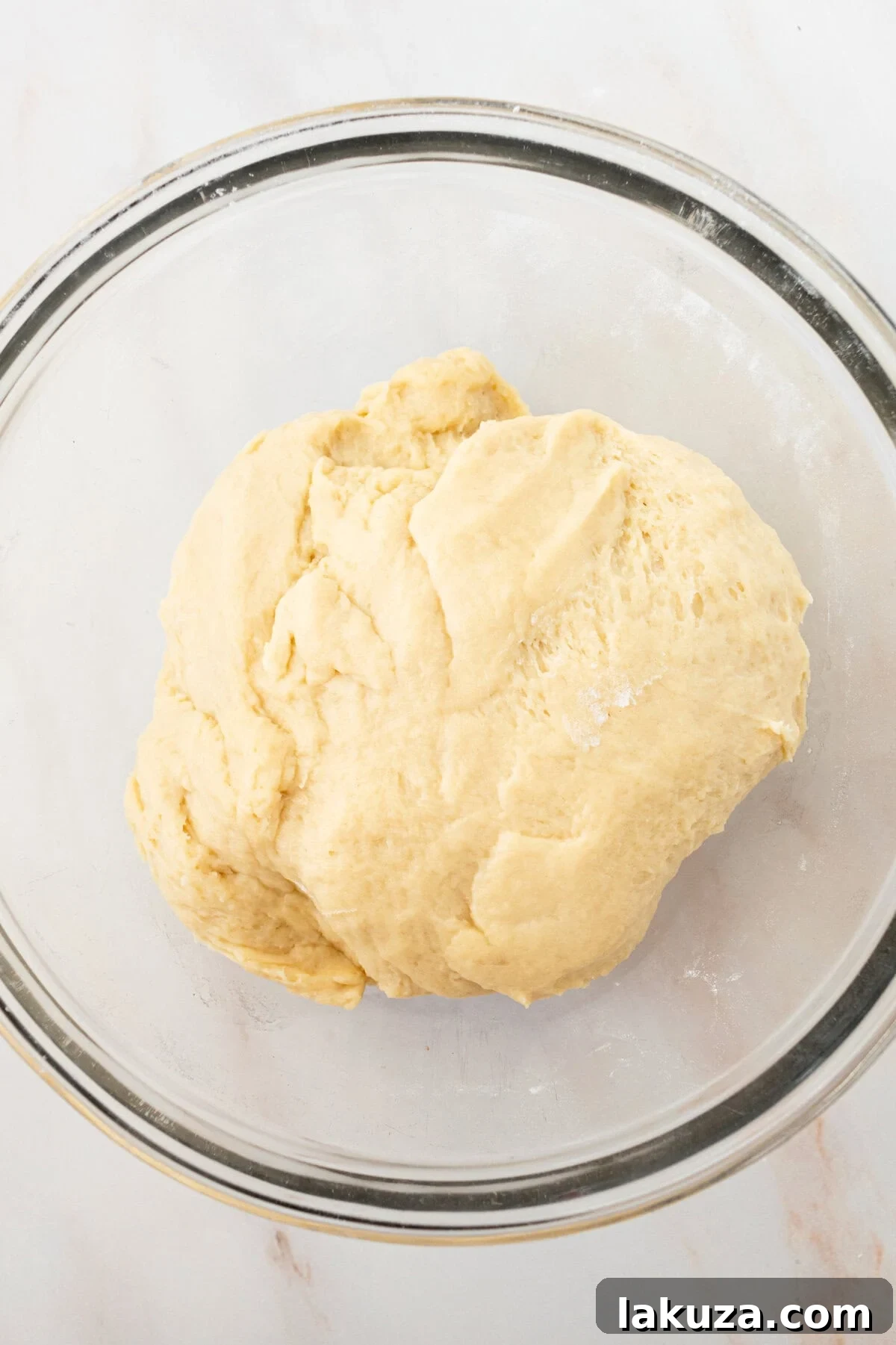 Heavenly Homemade Cinnamon Buns 8 Unrisen cinnamon roll dough in a mixing bowl, showcasing its smooth texture and readiness for the first proofing stage before it expands in size.