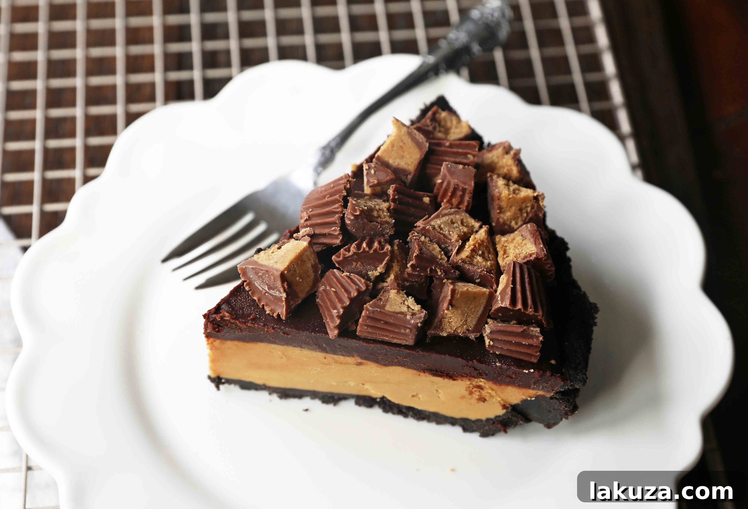 A slice of homemade chocolate peanut butter pie with an OREO cookie crust, creamy peanut butter mousse filling, and topped with chocolate ganache and peanut butter cups, ready to be served.