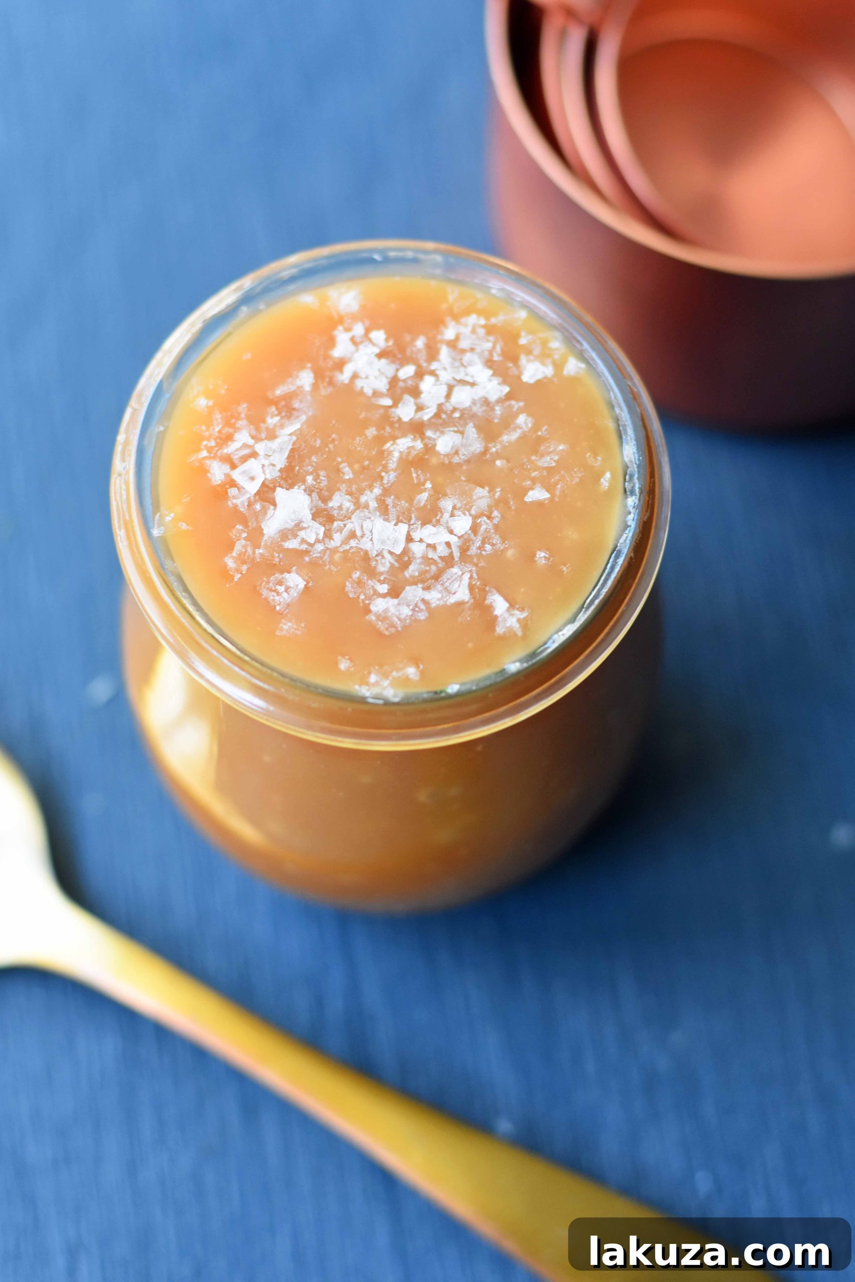 Homemade salted caramel sauce being drizzled over fresh apple pie filling, emphasizing the key ingredient that makes this pie exceptional.