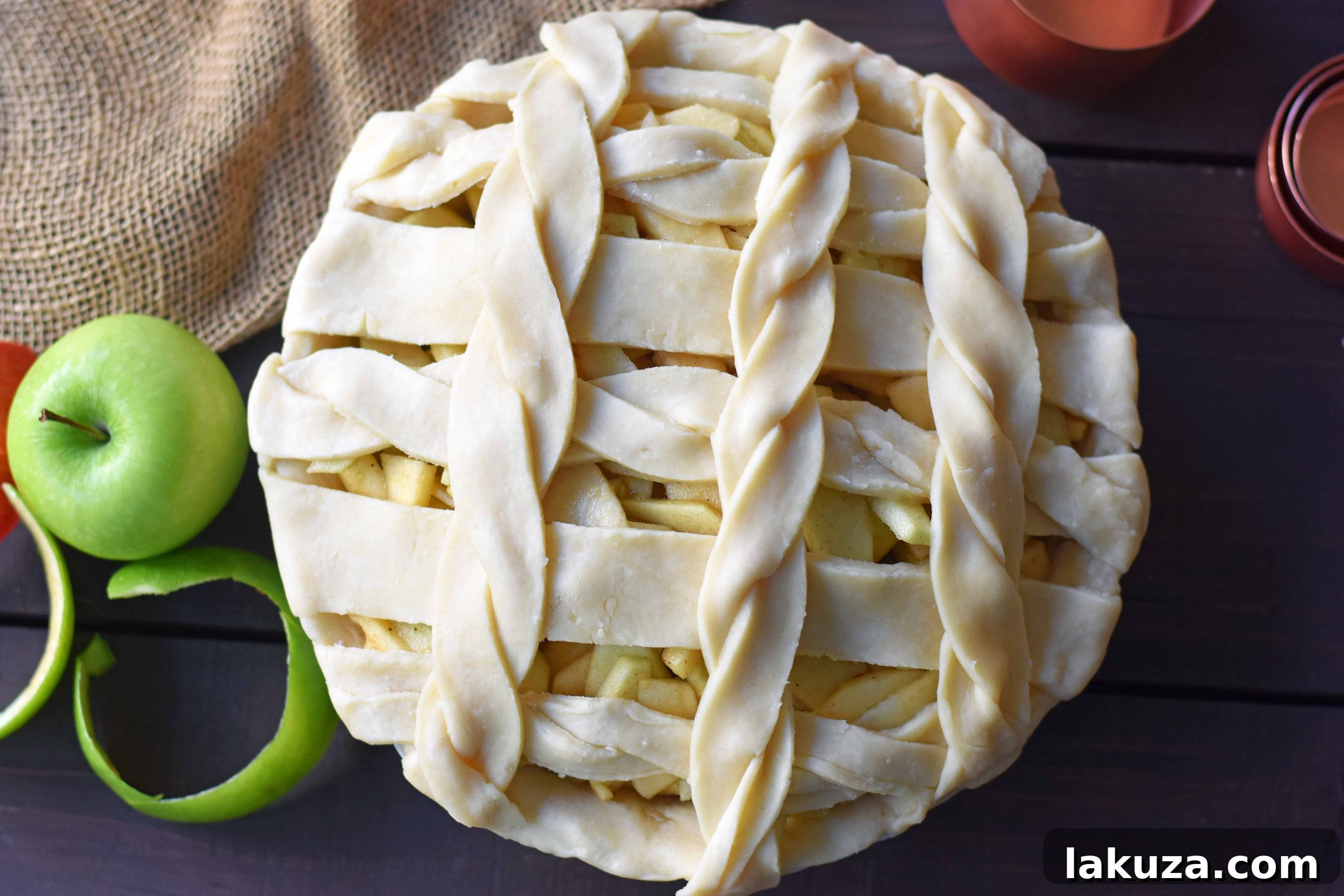 Two hands serving a slice of salted caramel apple pie onto a plate, highlighting the delightful experience of sharing this homemade treat.