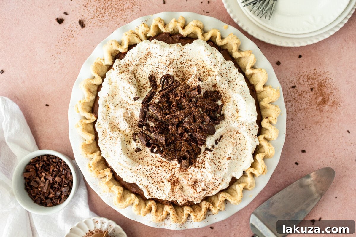 A close-up shot of a full Chocolate Cream Pie, with a focus on the fluffy whipped cream and chocolate garnishes.